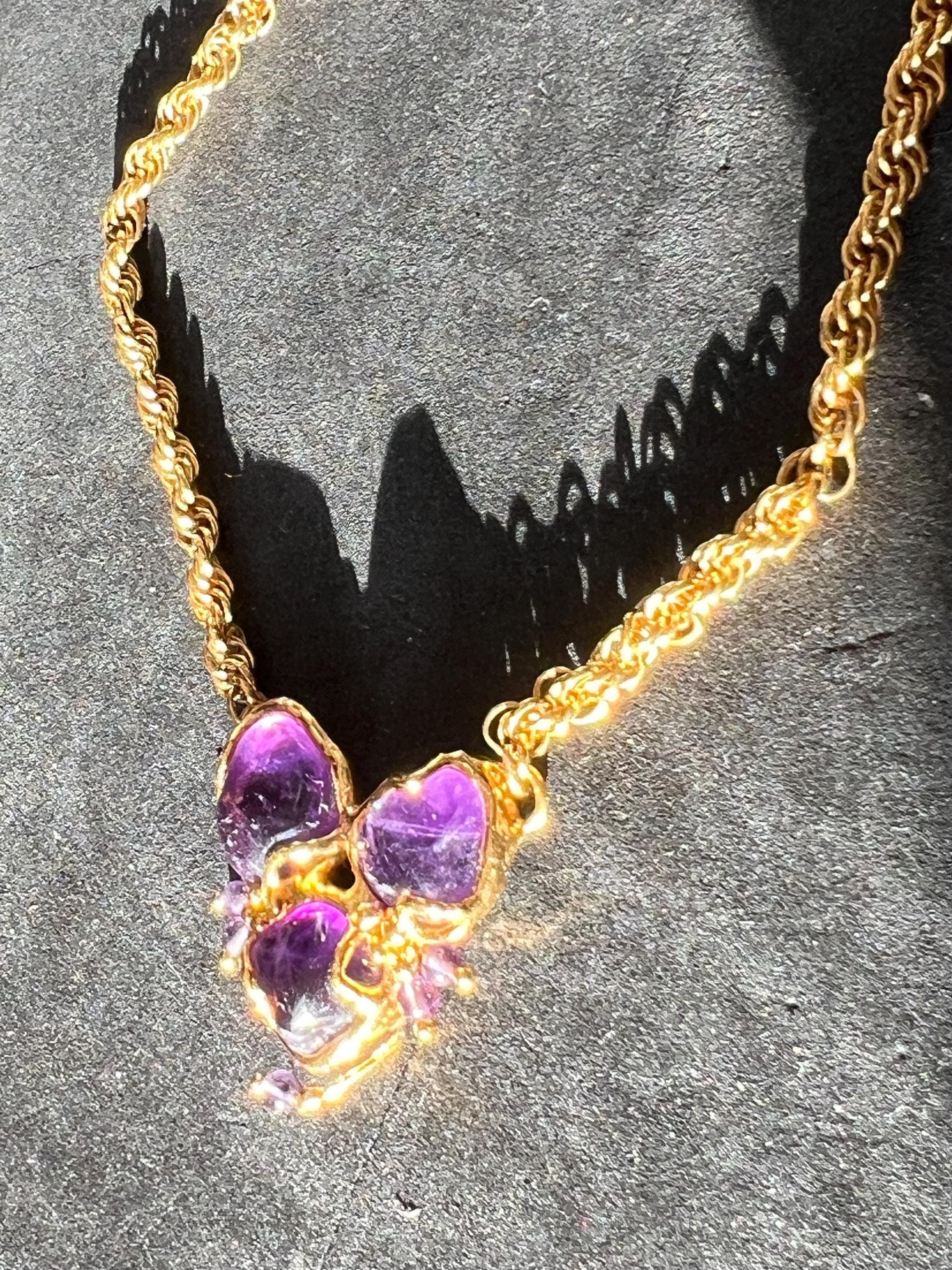 Product photo showing vintage 1990s gold-tone necklace with natural amethyst stones in a handcrafted pendant, feminine design.