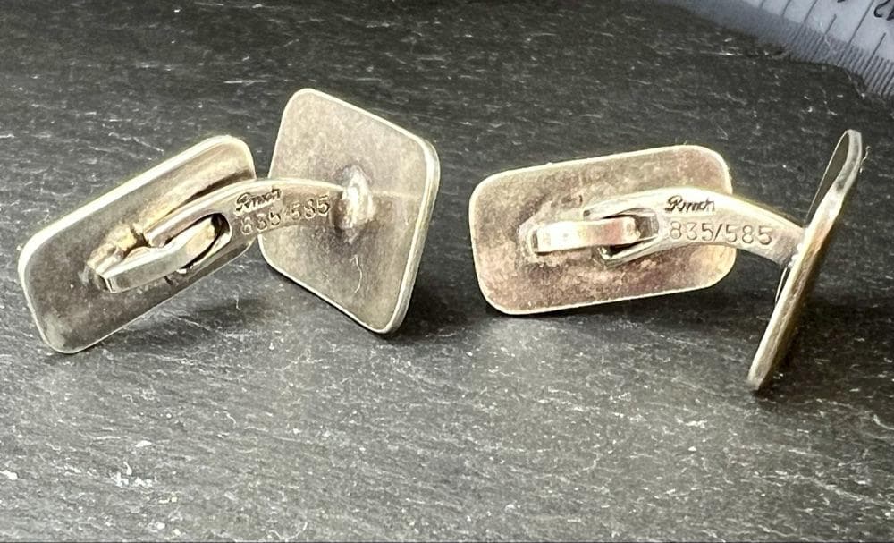 A close-up shot of a pair of rectangular vintage cufflinks. They are made of silver with a ridged gold-filled front. The back of one cufflink is visible, showing the engraved maker's mark "Rinch" and the metal stamps "835/585."