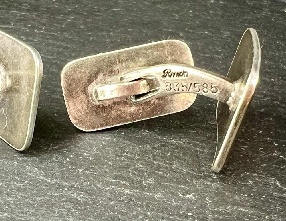 A close-up shot of a pair of rectangular vintage cufflinks. They are made of silver with a ridged gold-filled front. The back of one cufflink is visible, showing the engraved maker's mark "Rinch" and the metal stamps "835/585."