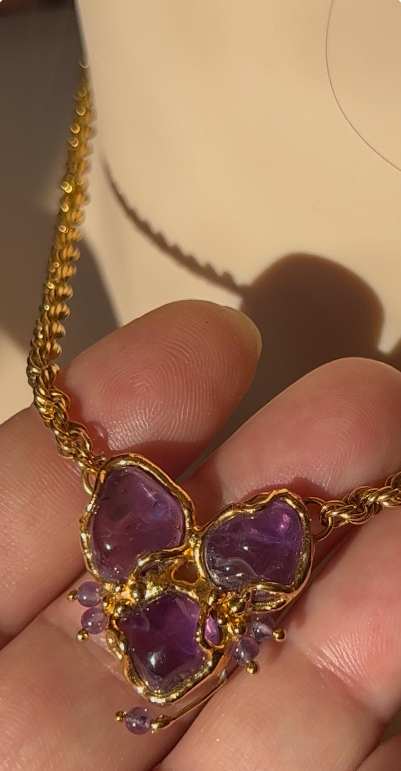 Product photo showing vintage 1990s gold-tone necklace with natural amethyst stones in a handcrafted pendant, feminine design. close up