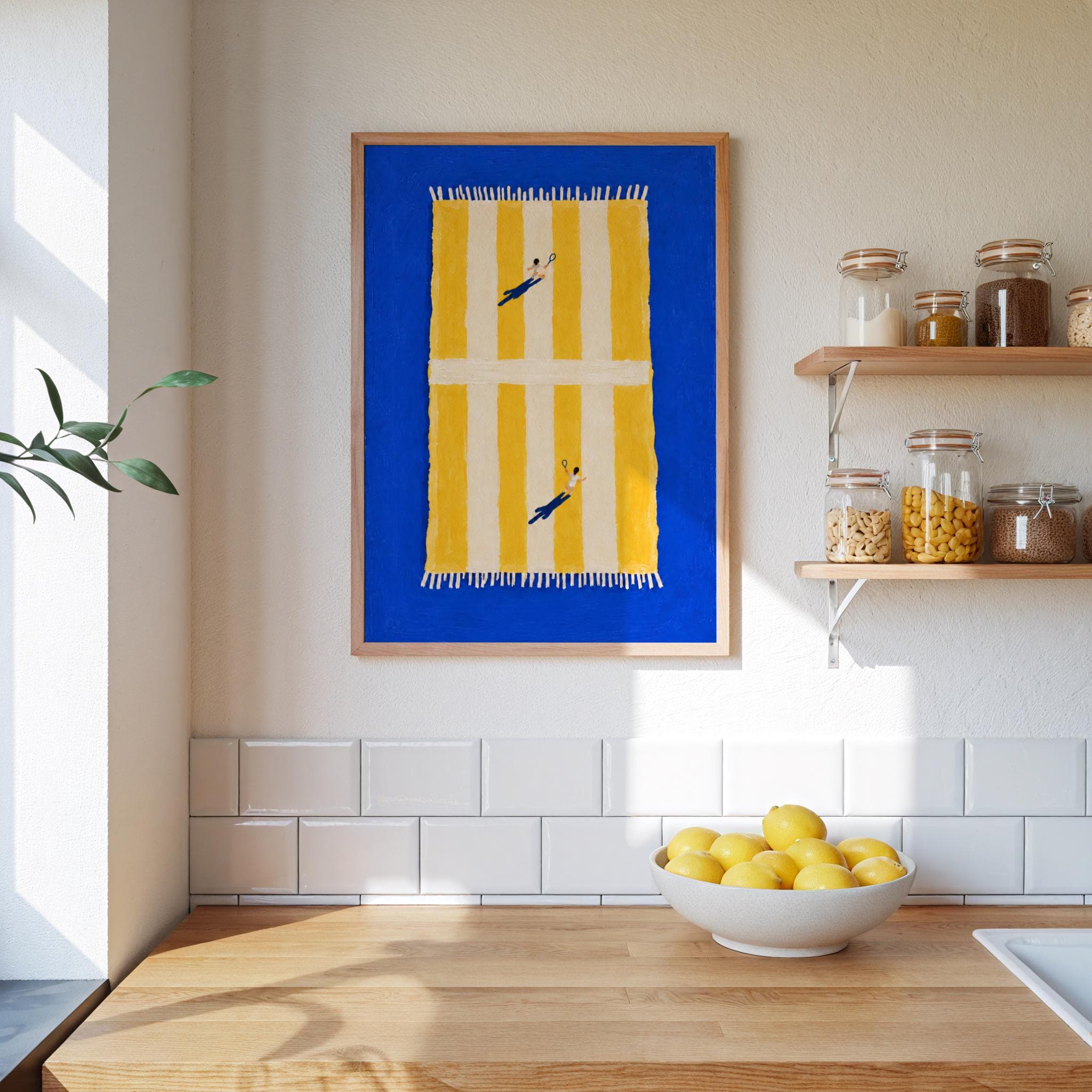 A framed wall art print featuring a vibrant blue background with a centered yellow and white striped beach towel. Two small figures are depicted on the towel, each holding a tennis racket, creating a top-down view of a tennis court.