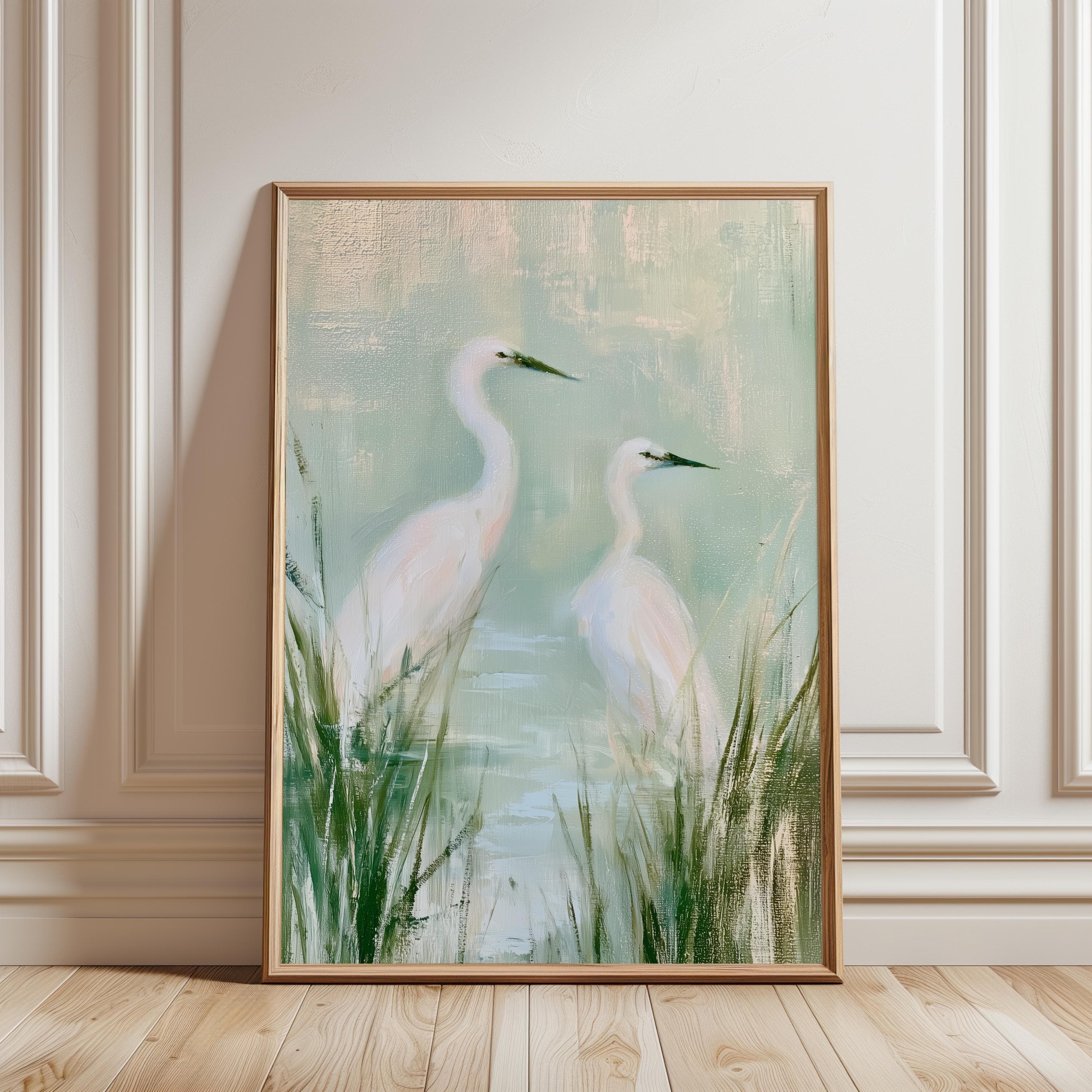 A framed vertical wall art print featuring two white egrets standing in a marshy landscape with tall green grasses and soft light blue and pale green water tones, captured in a painterly style with visible brushstrokes.