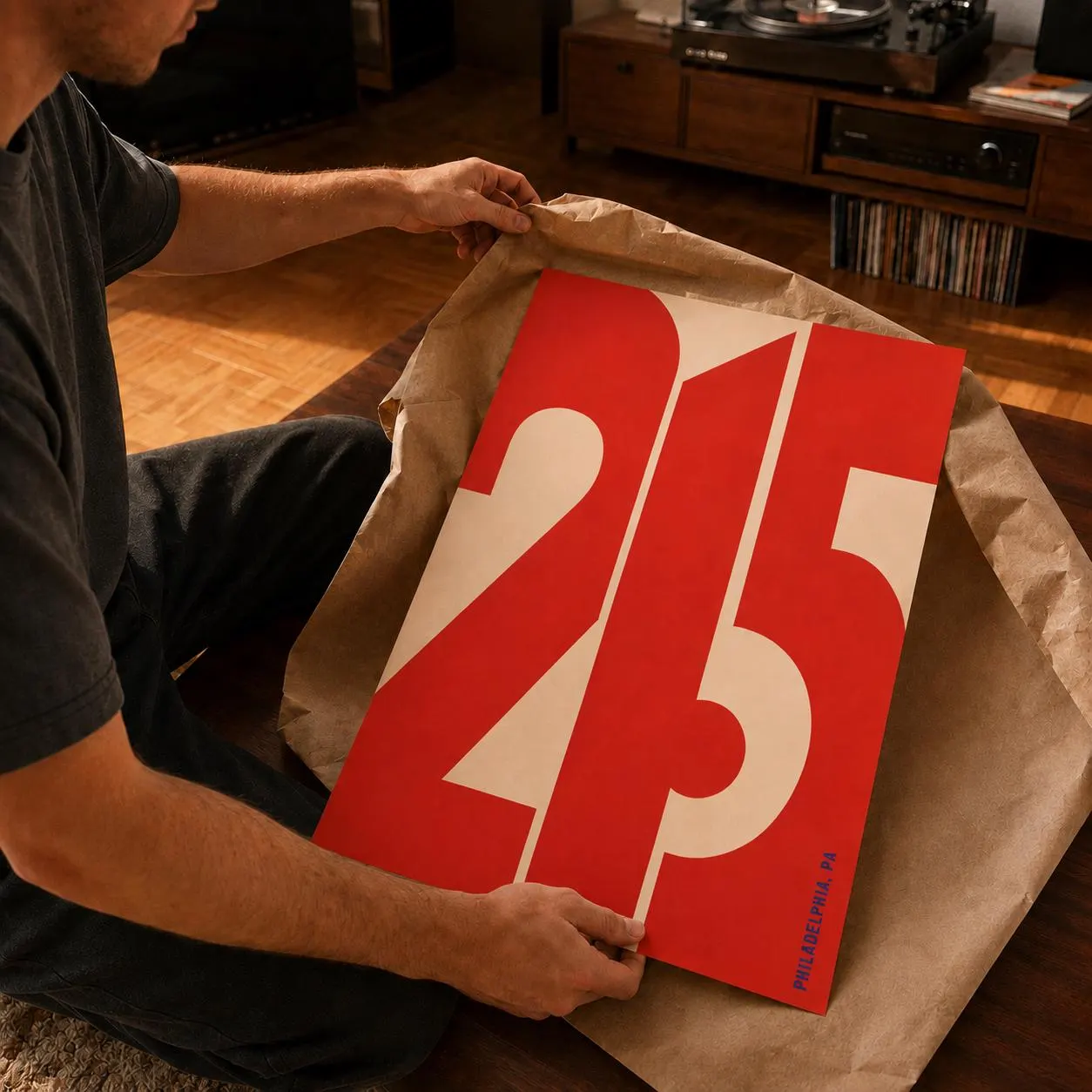 A rectangular poster featuring the bold red numbers 215 printed on a cream background. The design includes the text PHILADELPHIA, PA in small blue letters at the bottom right corner. The poster is displayed on brown paper.