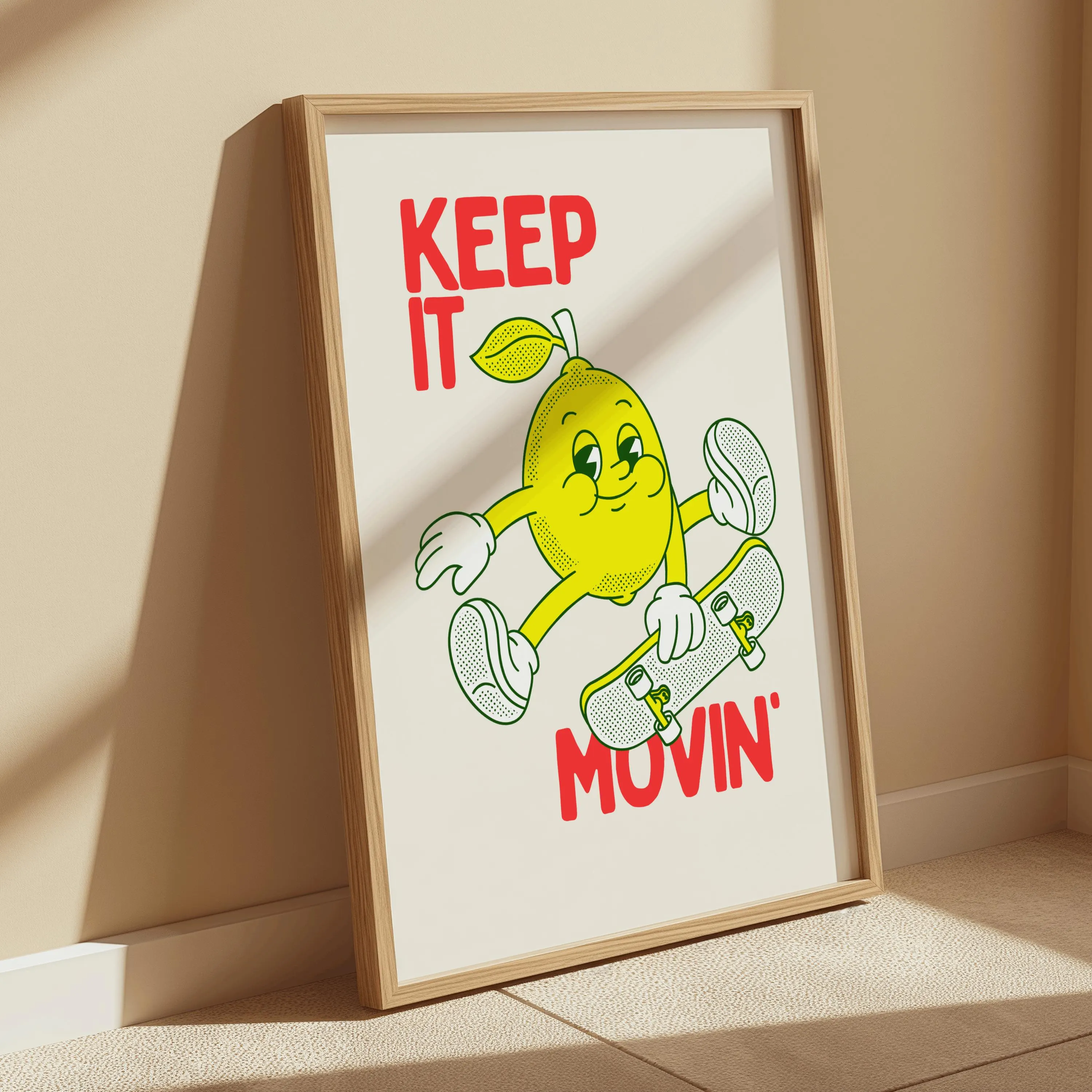 Framed art print featuring a cartoon lemon character skateboarding. The lemon is yellow with white gloves and shoes, and the text "KEEP IT MOVIN'" is in red. The artwork is set against an off-white background.