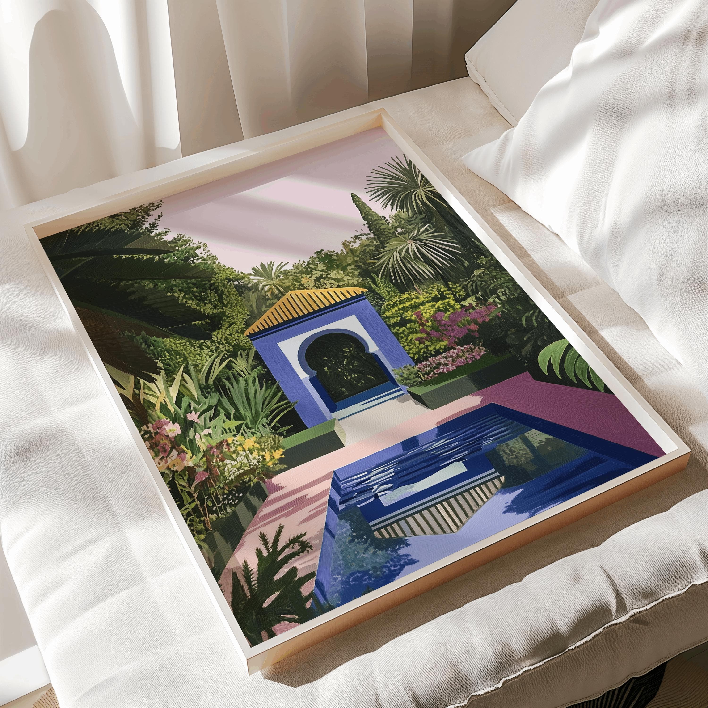 A framed art print featuring a vibrant garden scene with a blue Moorish-style structure, a rectangular pool reflecting the architecture, lush green palm trees, and colorful flowering plants under a soft pink sky.