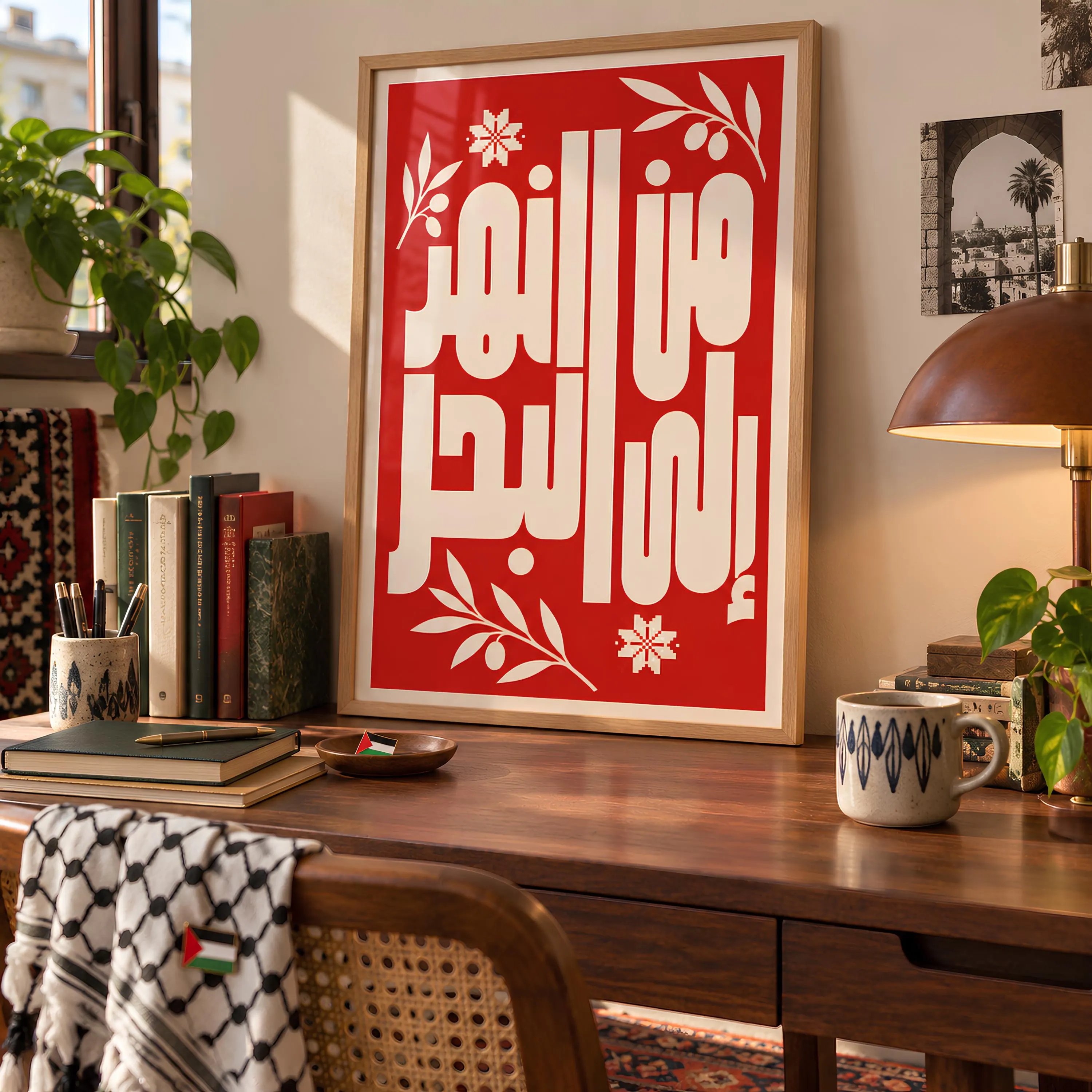 A framed vertical poster with a bright red background featuring bold white Arabic calligraphy and white olive branch illustrations. The text is centered within a light wood frame.