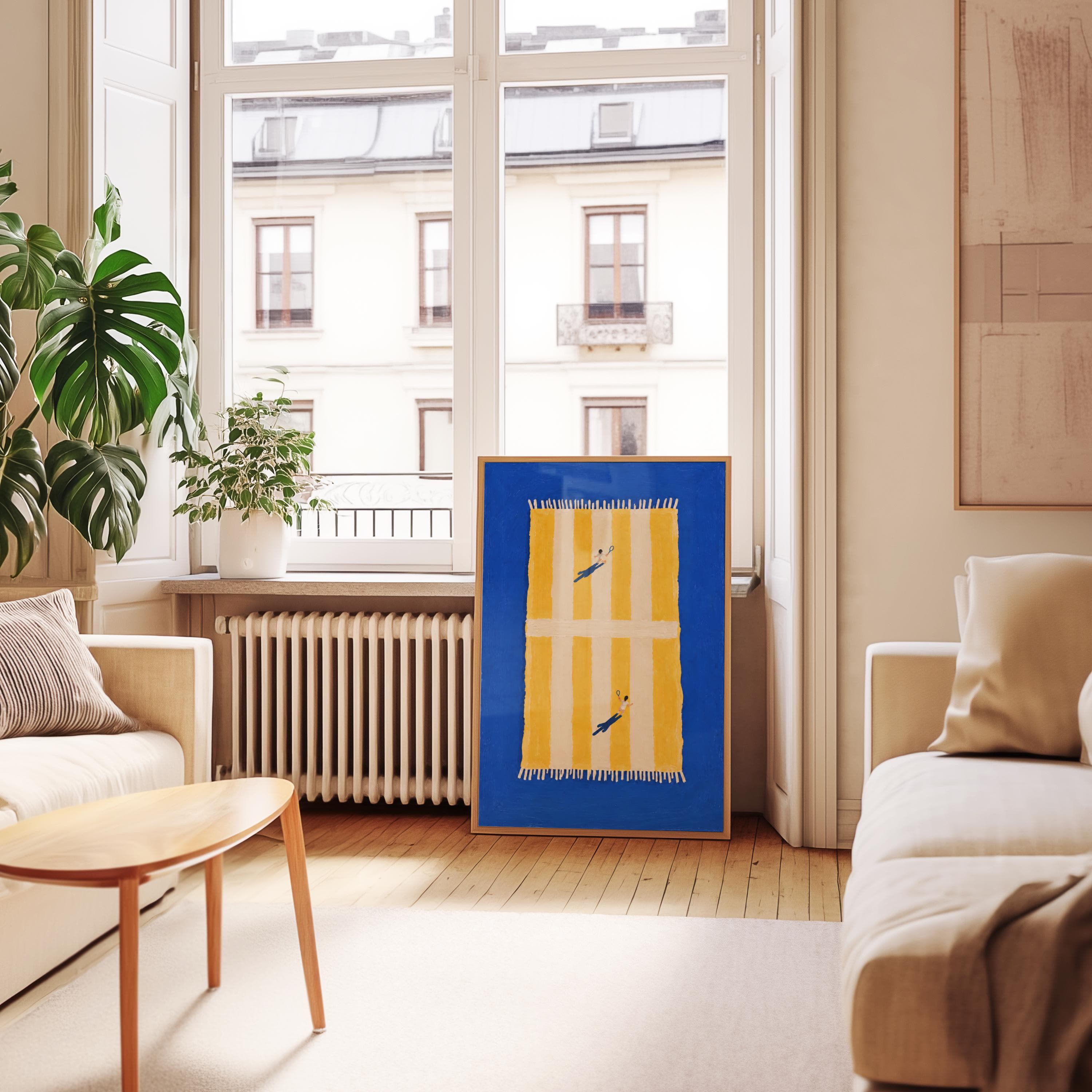 A rectangular, playful framed print featuring a vibrant blue background with a central yellow and white striped towel graphic. Two small figures are depicted playing tennis on the towel, which has white fringe on both ends.
