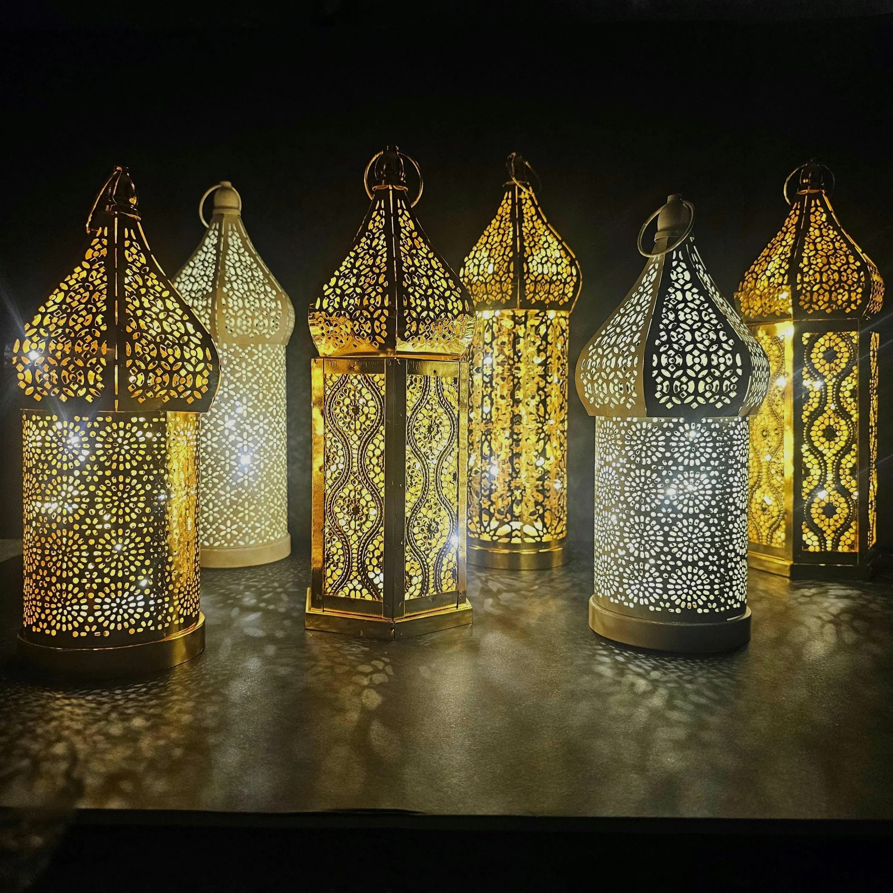 A selection of white and gold metal lanterns with distinctive geometric patterns. Available in various sizes, these lanterns add a cozy and festive vibe for Ramadan and Eid.