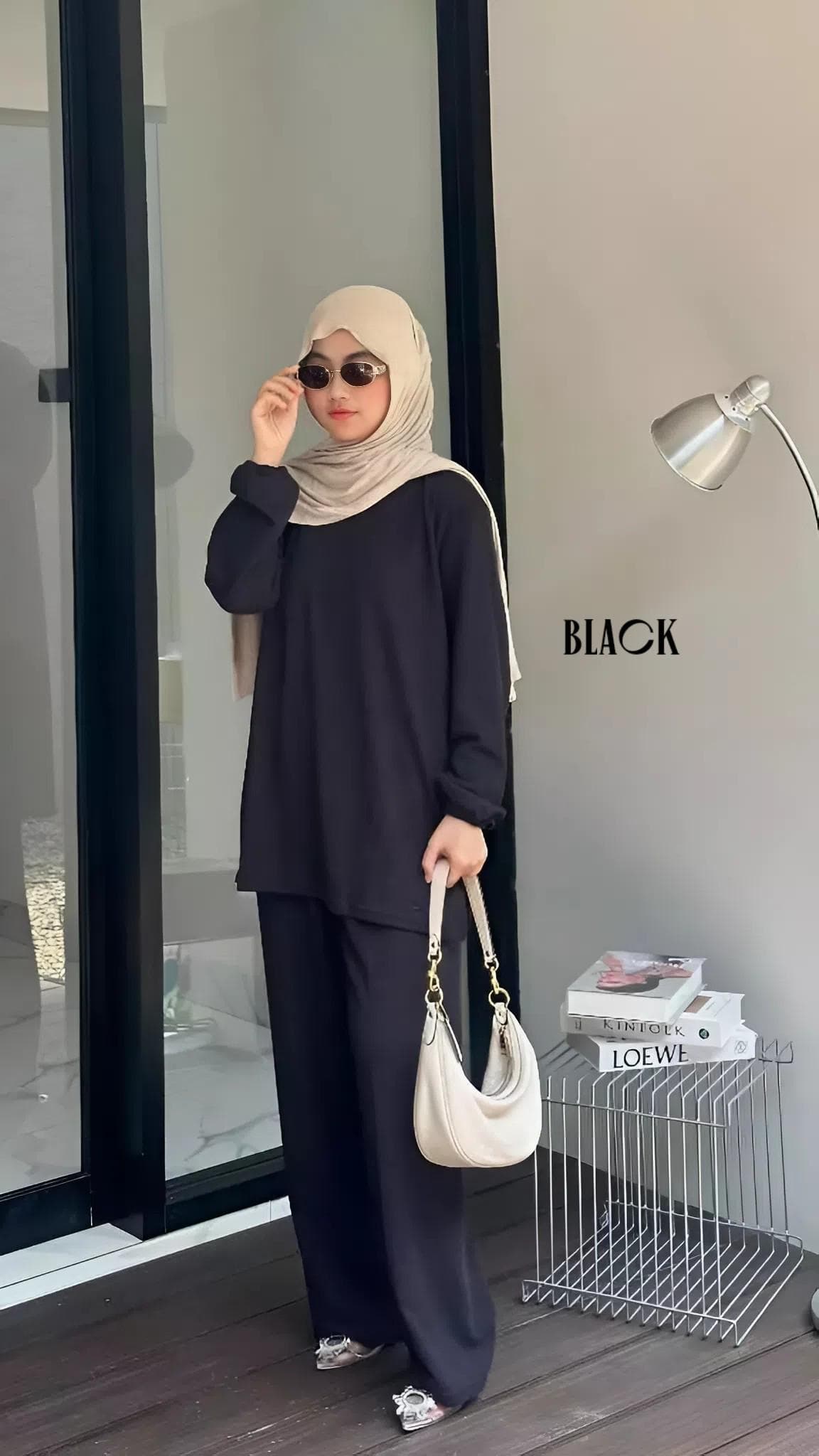 Woman wearing a modest knit lounge set with a long sleeve top and wide leg pants, styled with a hijab and handbag.