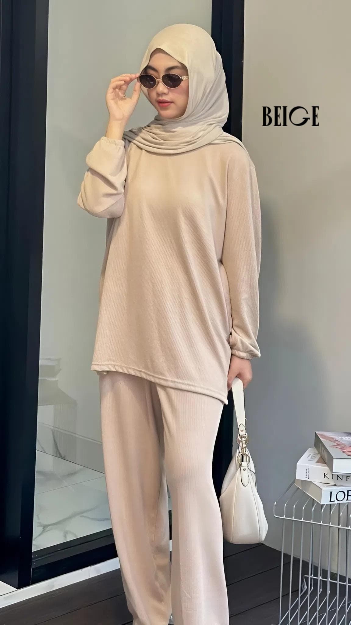 Woman wearing a modest knit lounge set with a long sleeve top and wide leg pants, styled with a hijab and handbag.