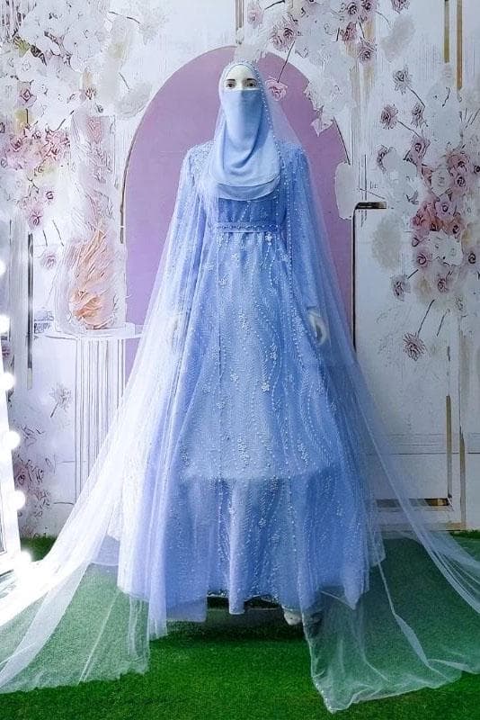 A modest satin and embroidered tulle wedding dress with long flowing skirt, pearl details, and matching veil displayed in a bridal studio.