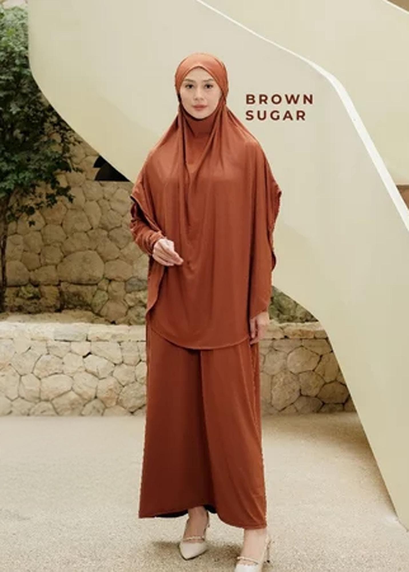 An oversized dark grey jersey abaya set with a matching long khimar worn by a woman in a minimalist setting.