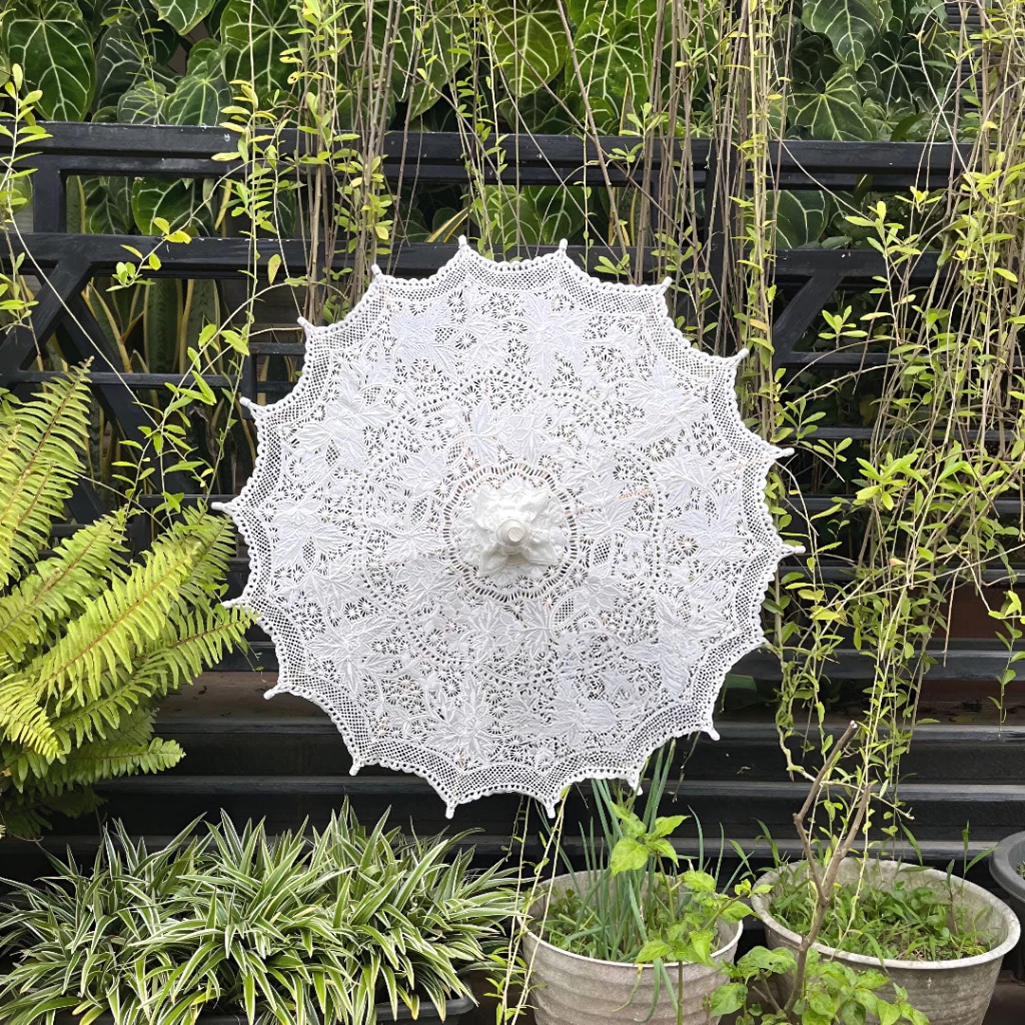 White embroidered lace parasol displayed outdoors with a wooden handle and floral pattern.