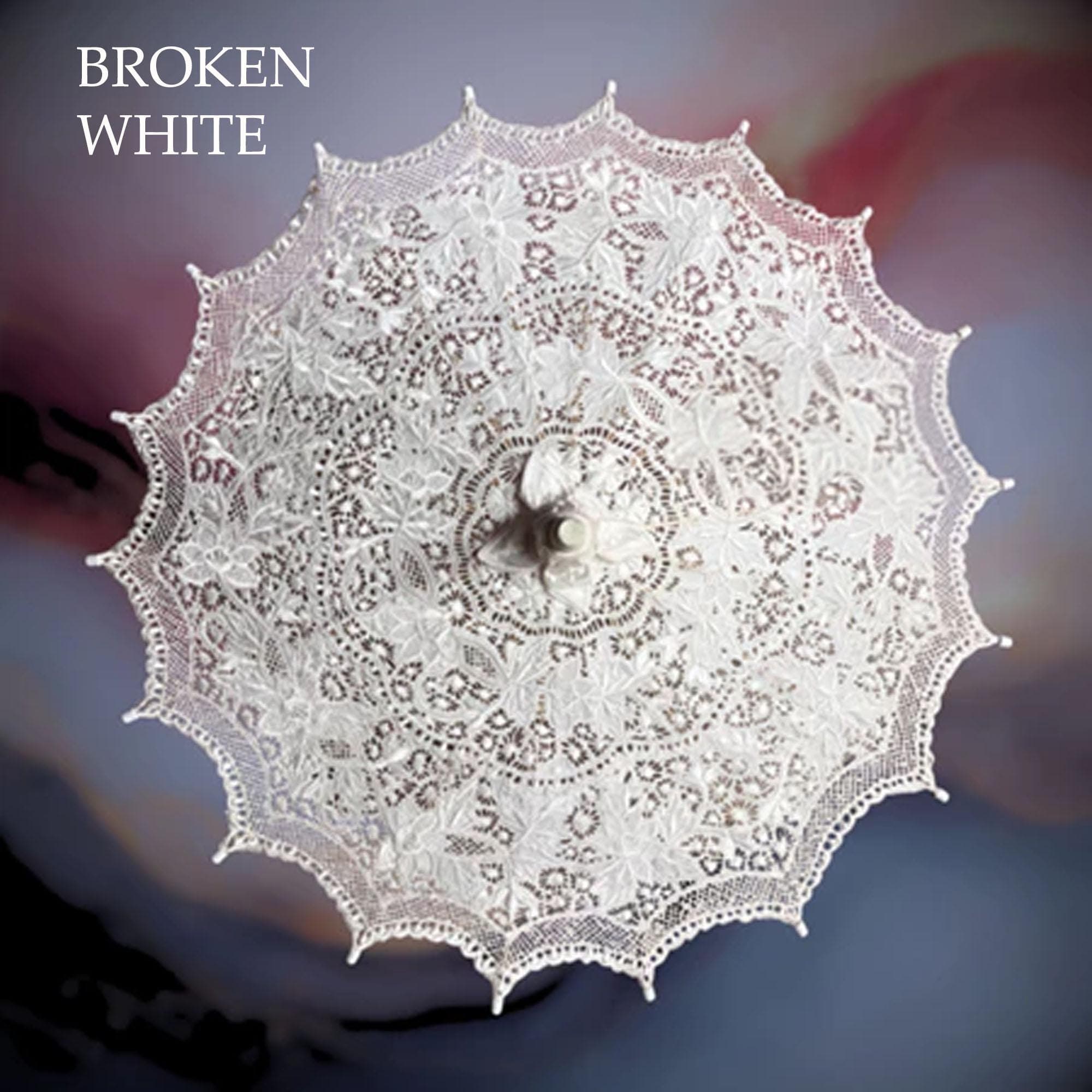 White embroidered lace parasol displayed outdoors with a wooden handle and floral pattern.