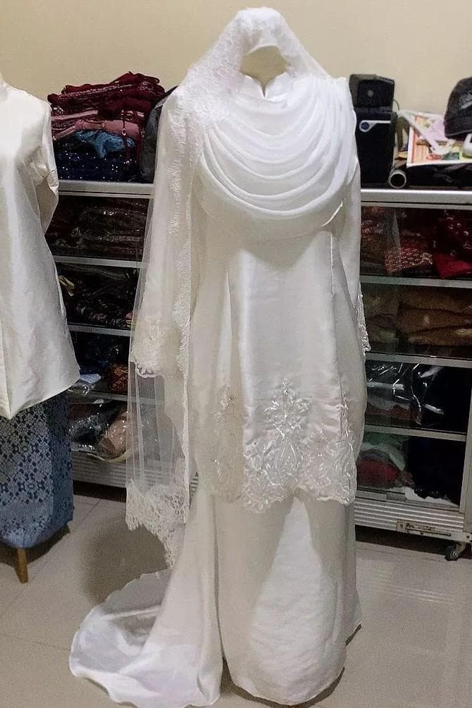 A white embroidered modest long dress with matching veil displayed on a mannequin.