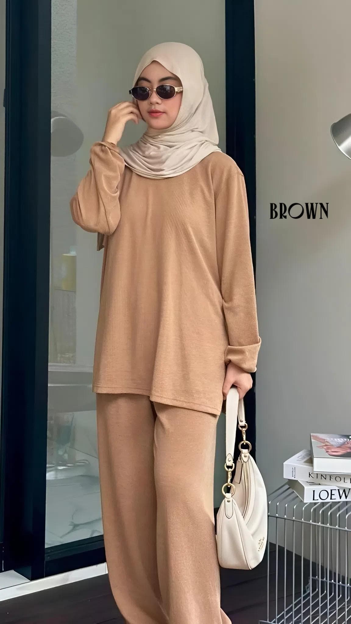 Woman wearing a modest knit lounge set with a long sleeve top and wide leg pants, styled with a hijab and handbag.