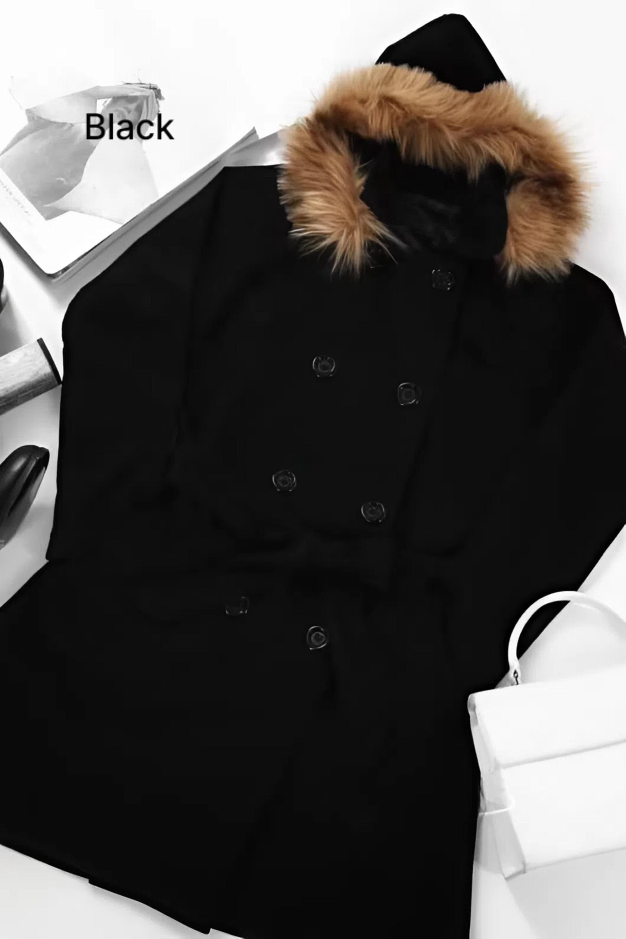 Woman wearing a mocca long fleece winter coat with detachable faux fur hood and belt, standing outdoors in greenery
