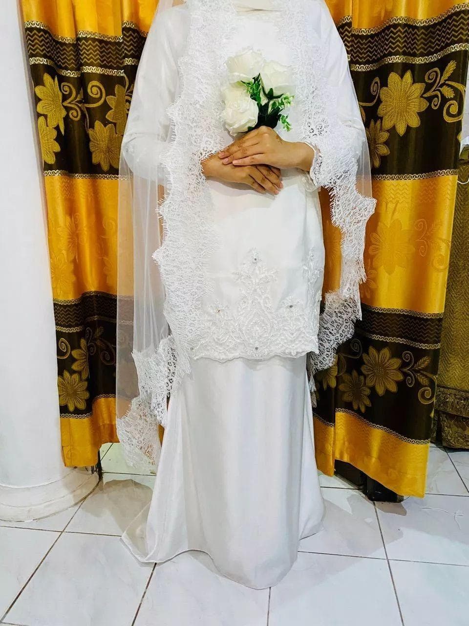 A white embroidered modest long dress with matching veil displayed on a mannequin.