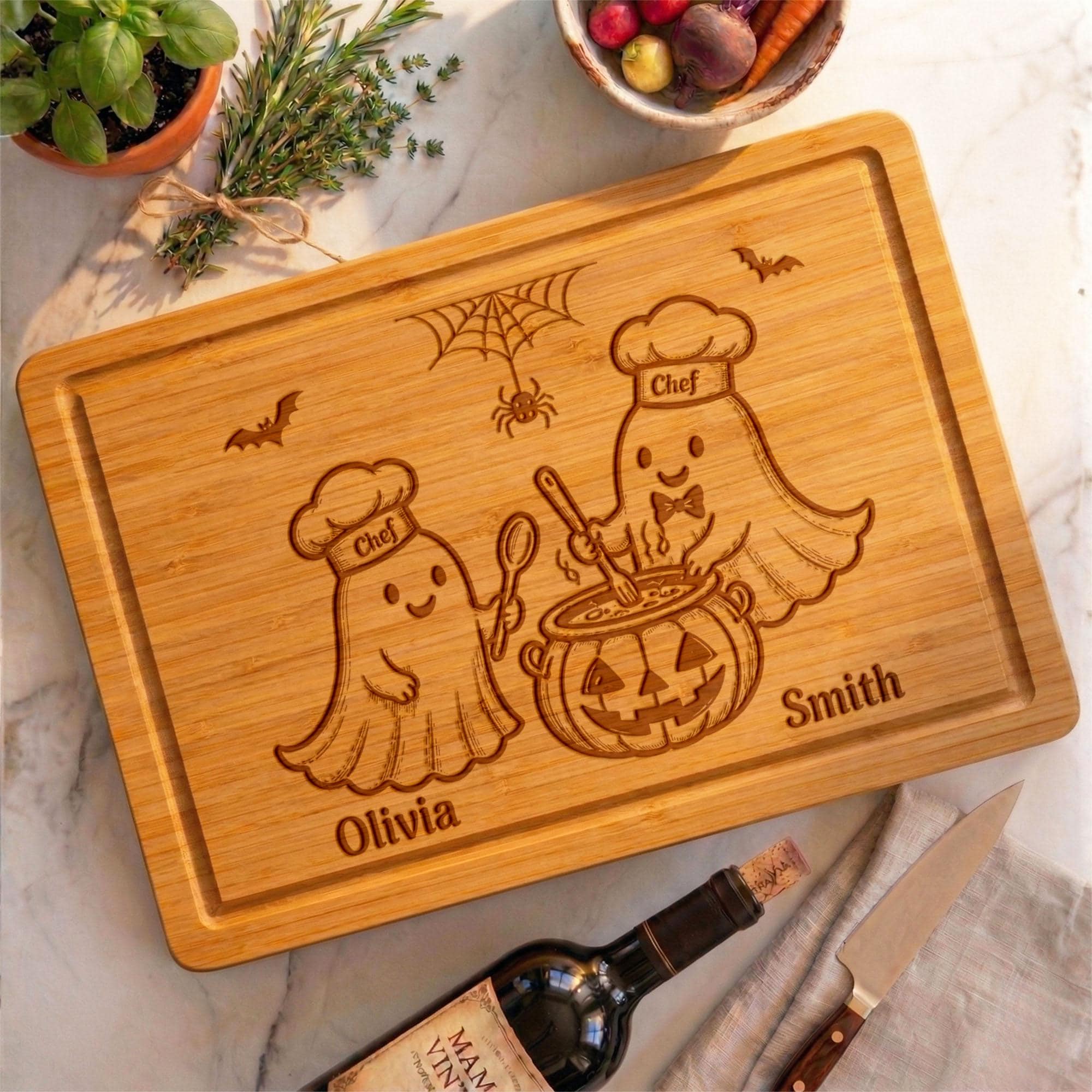 May include: A rectangular bamboo cutting board featuring laser-engraved illustrations of two ghosts wearing chef hats, one stirring a jack-o'-lantern pot. The board includes the text Olivia, Smith, and Chef, along with a spider web and bats.