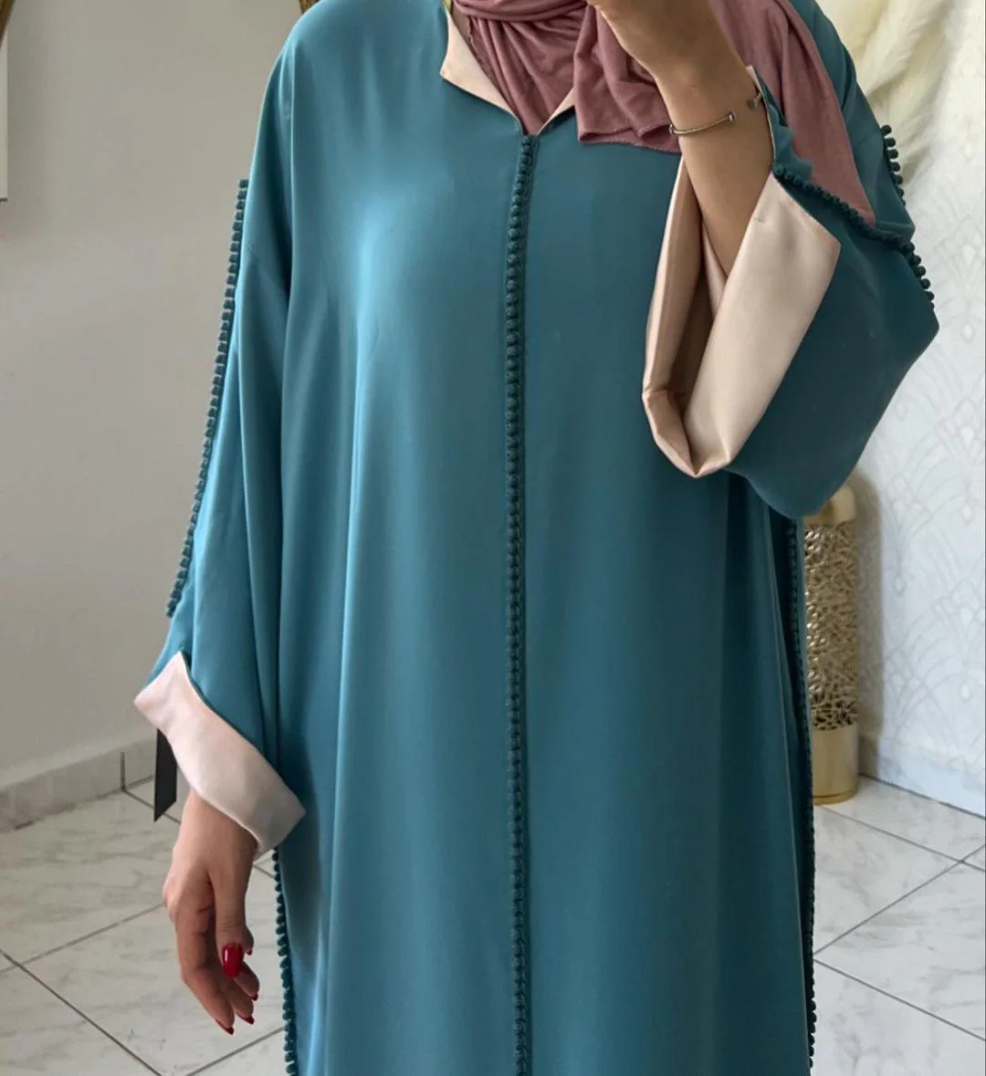 Side view of the teal green djellaba showing the relaxed silhouette and pink trim at the neckline