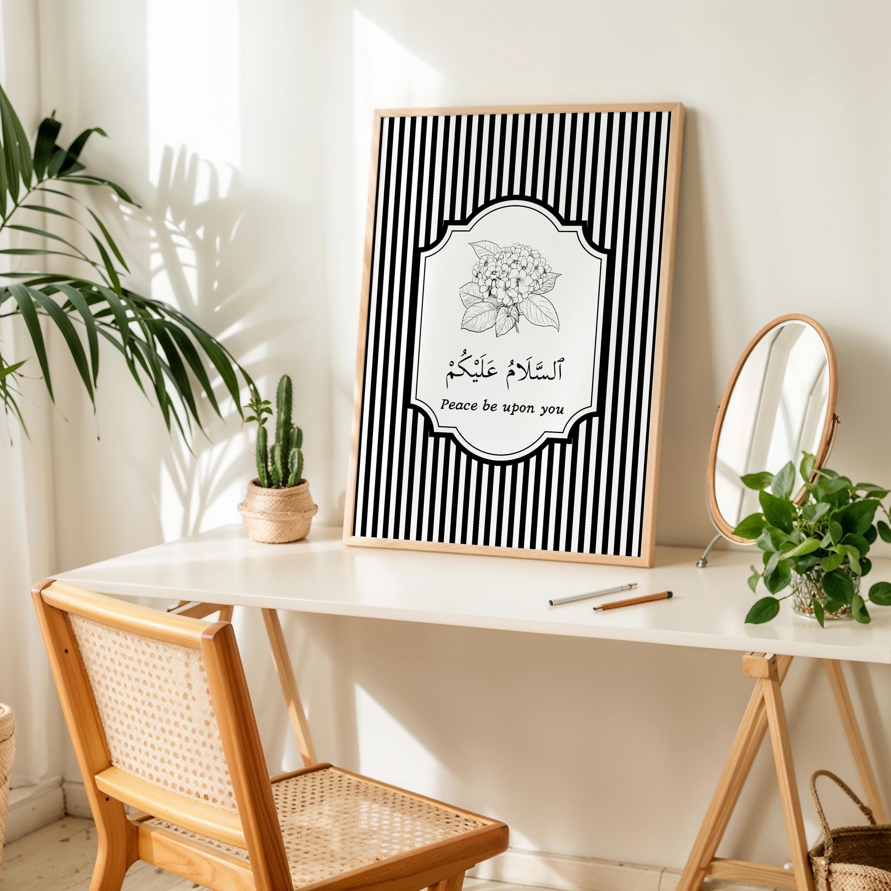 Minimalist Islamic wall art print with black and white vertical stripes as the background. The center features a floral illustration above Arabic calligraphy that reads “As-salamu Alaykum” (Peace be upon you), with the English translation written below. Modern monochrome design in a wooden frame, perfect for Muslim home decor or entryway wall art.