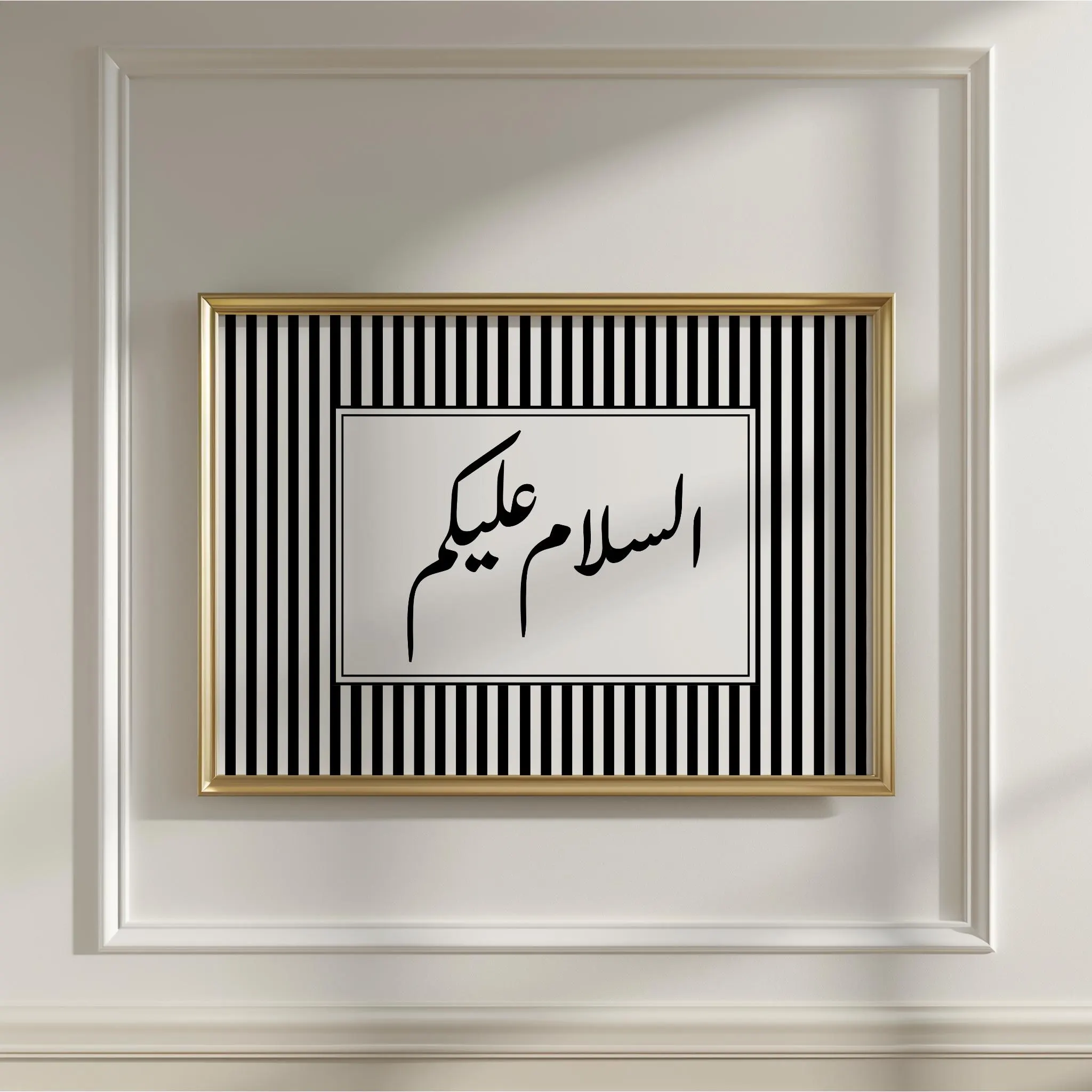 An islamic wall art featuring a centered text panel with elegant black Arabic calligraphy of the greeting "As-salamu alaykum" (Peace be upon you). The calligraphy is set against a white background and is framed by a striking pattern of vertical black and white stripes, creating a modern, minimalist-meets-traditional aesthetic.