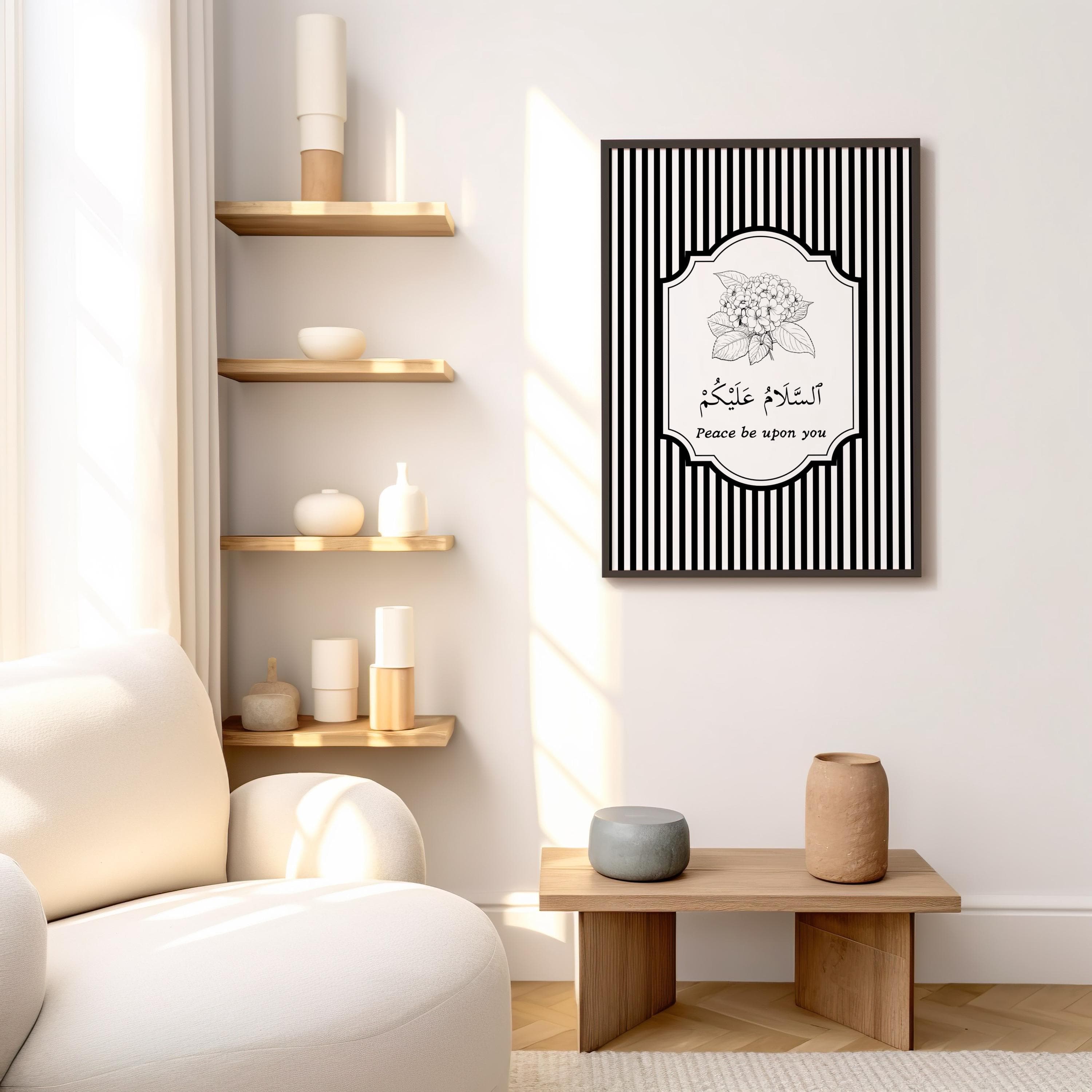 Minimalist Islamic wall art print with black and white vertical stripes as the background. The center features a floral illustration above Arabic calligraphy that reads “As-salamu Alaykum” (Peace be upon you), with the English translation written below. Modern monochrome design in a wooden frame, perfect for Muslim home decor or entryway wall art.