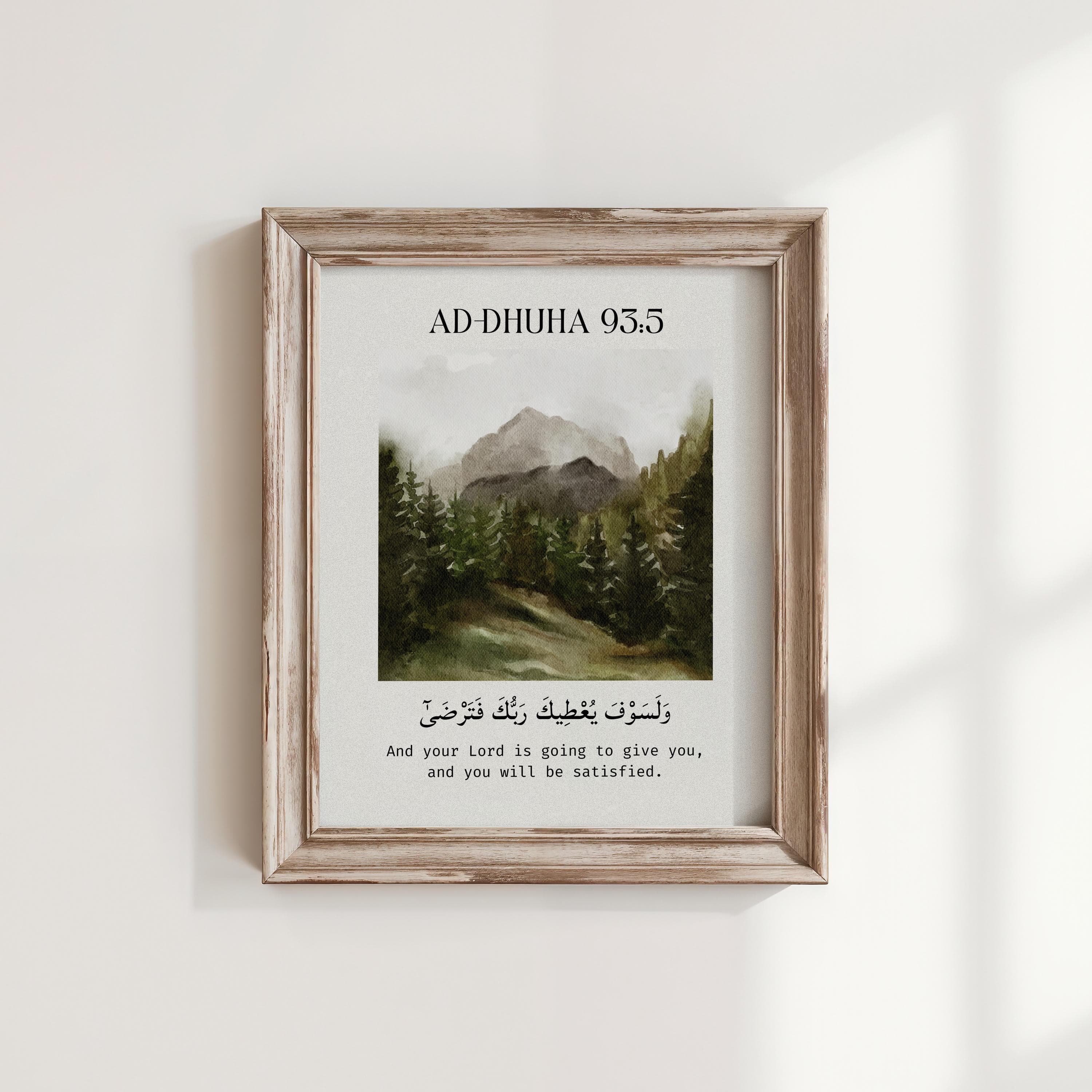 Islamic wall art print featuring Surah Ad-Dhuha 93:5 with Arabic and English translation: “And your Lord is going to give you, and you will be satisfied.” Centered above a watercolor-style landscape of mountains and pine trees, framed in light wood against a minimalist off-white wall, capturing a serene and spiritual vibe.