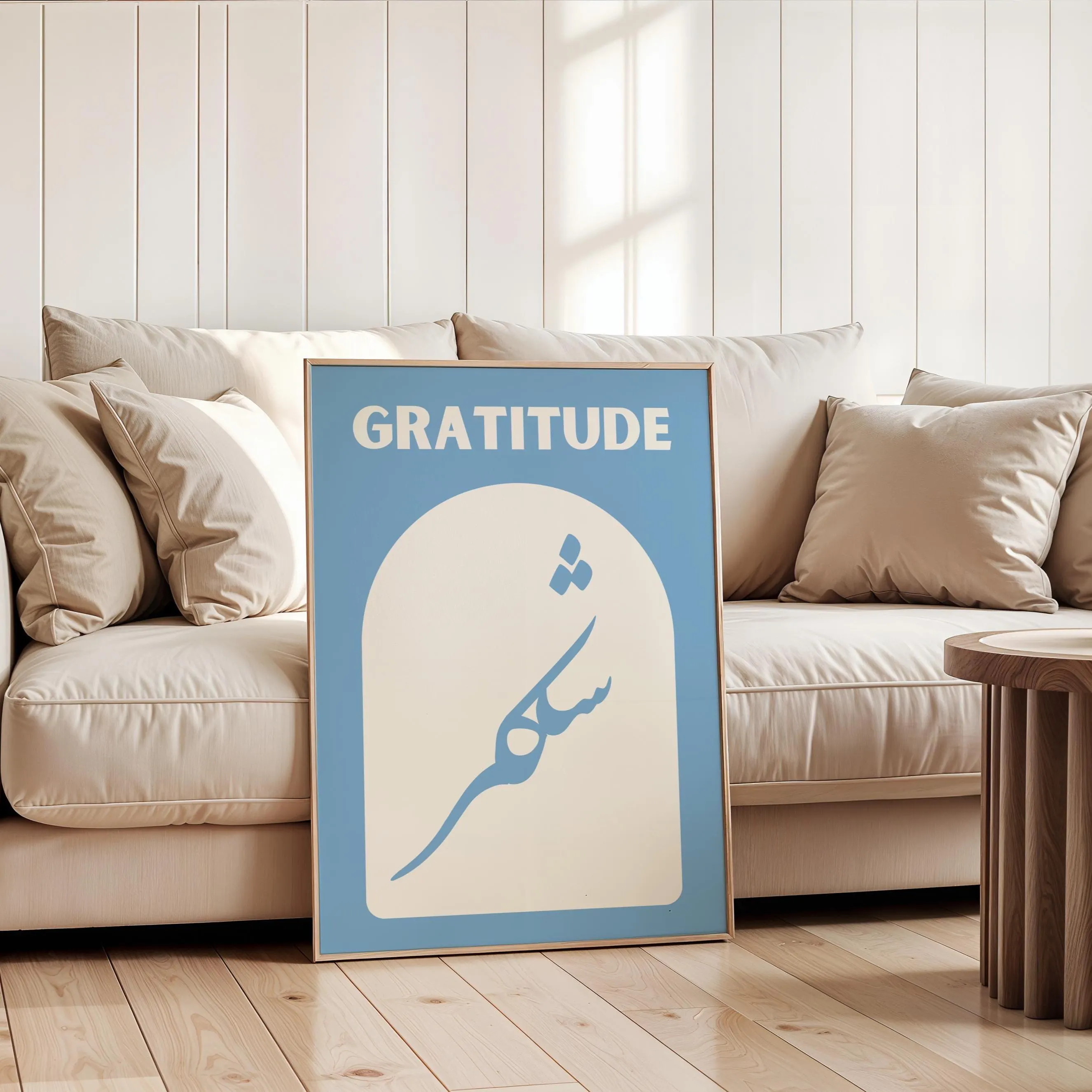 The artwork features a soft blue background featuring the word "GRATITUDE" in bold light beige letters at the top and the Arabic word for gratitude, "shukr" written elegantly below, inside an arched shape.