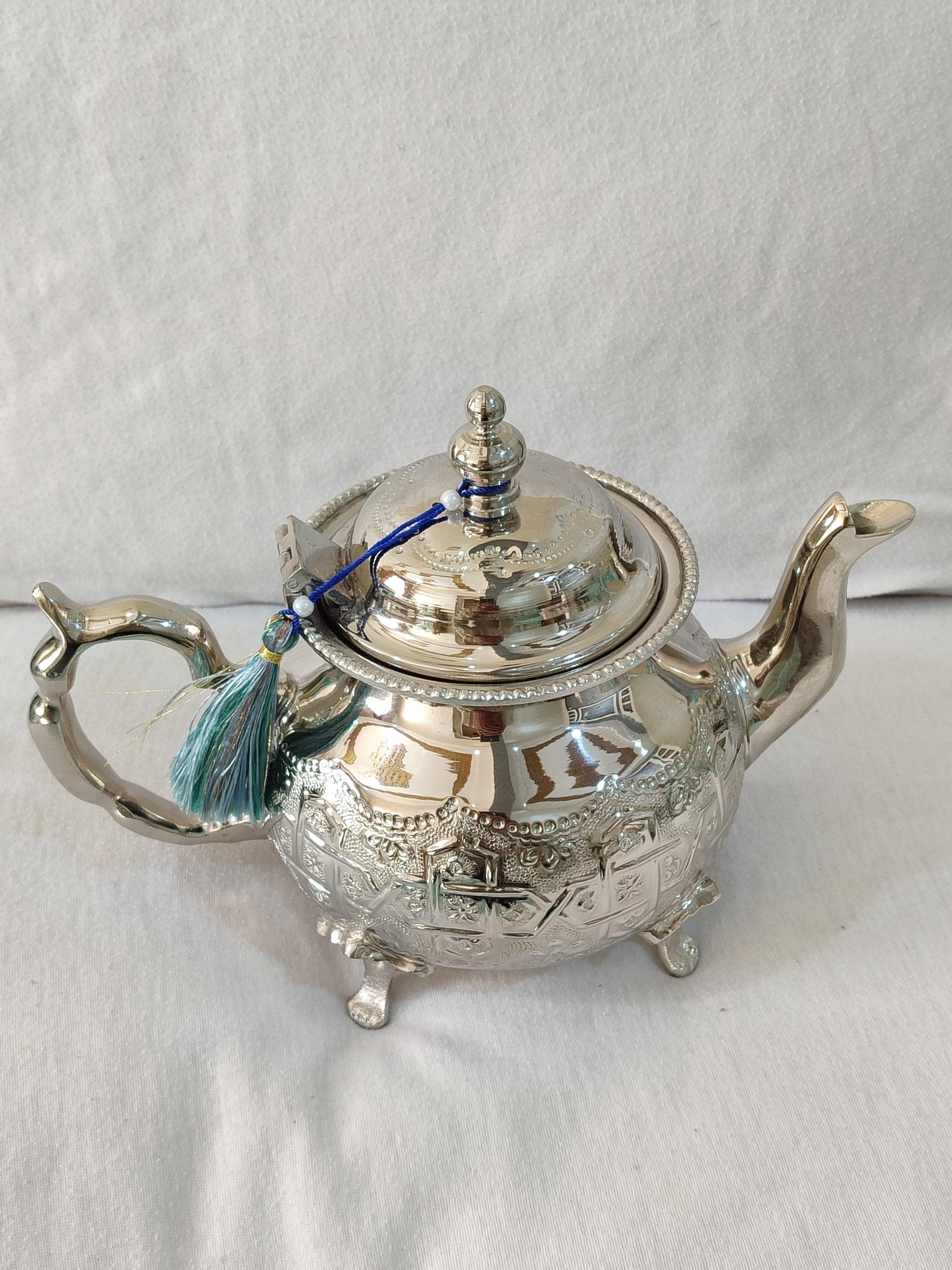 This complete Moroccan tea set includes a main antique teapot with matching serving tray and six traditional glasses. The arabic teapot design features elaborate filigree work and hand-chased patterns reminiscent of vintage teapot Morocco pieces. Crafted from premium silver brass materials, the set develops a beautiful patina over time. The teapot's generous capacity makes it perfect for hosting gatherings where Moroccan mint tea is the star. Each component is designed to complement the others