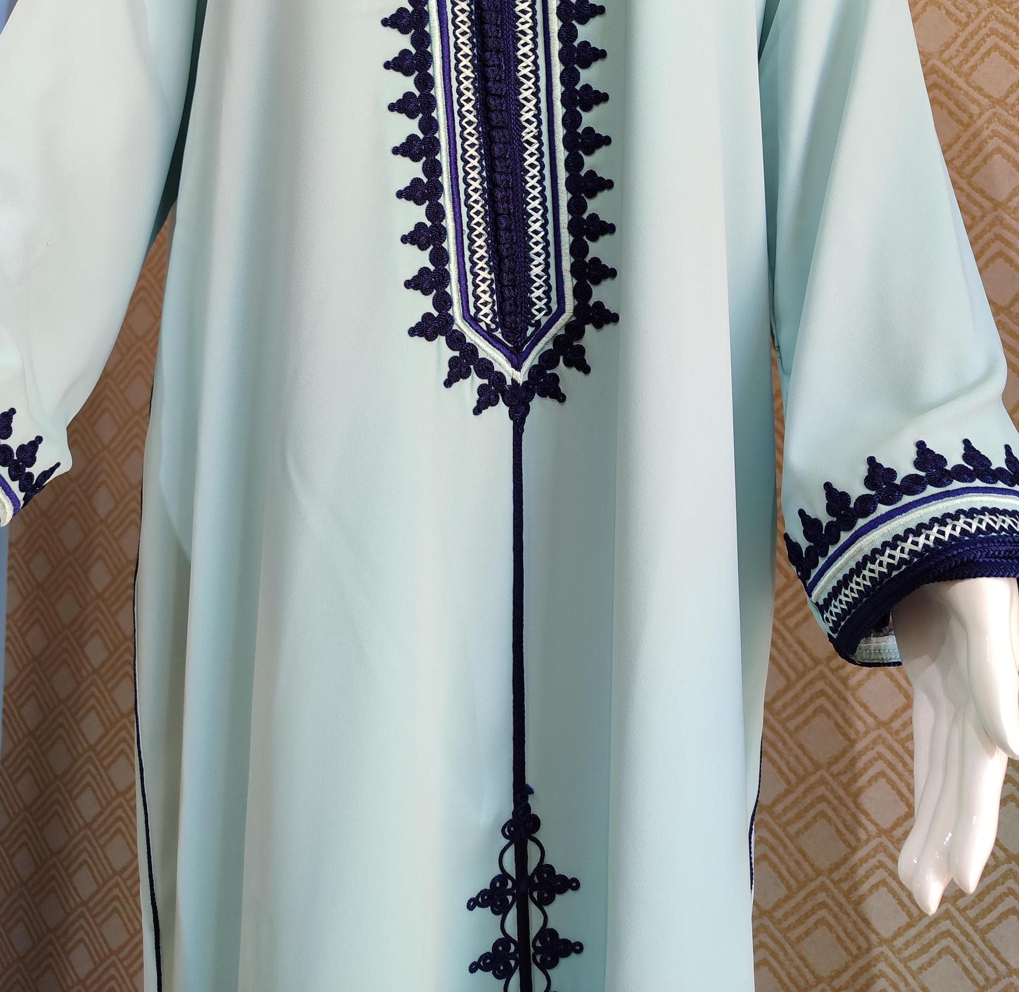The embroidery on our Moroccan jellaba creates a tactile experience that tells a story through touch. This jellaba handbeaded masterpiece features geometric patterns around the neckline that form a symmetrical design extending down the front. When touching the women jellaba winter version, you'll feel thicker embroidery threads creating raised patterns that form traditional Moroccan motifs. The patterns on this djellaba for wedding occasions include small diamond shapes and flowing lines