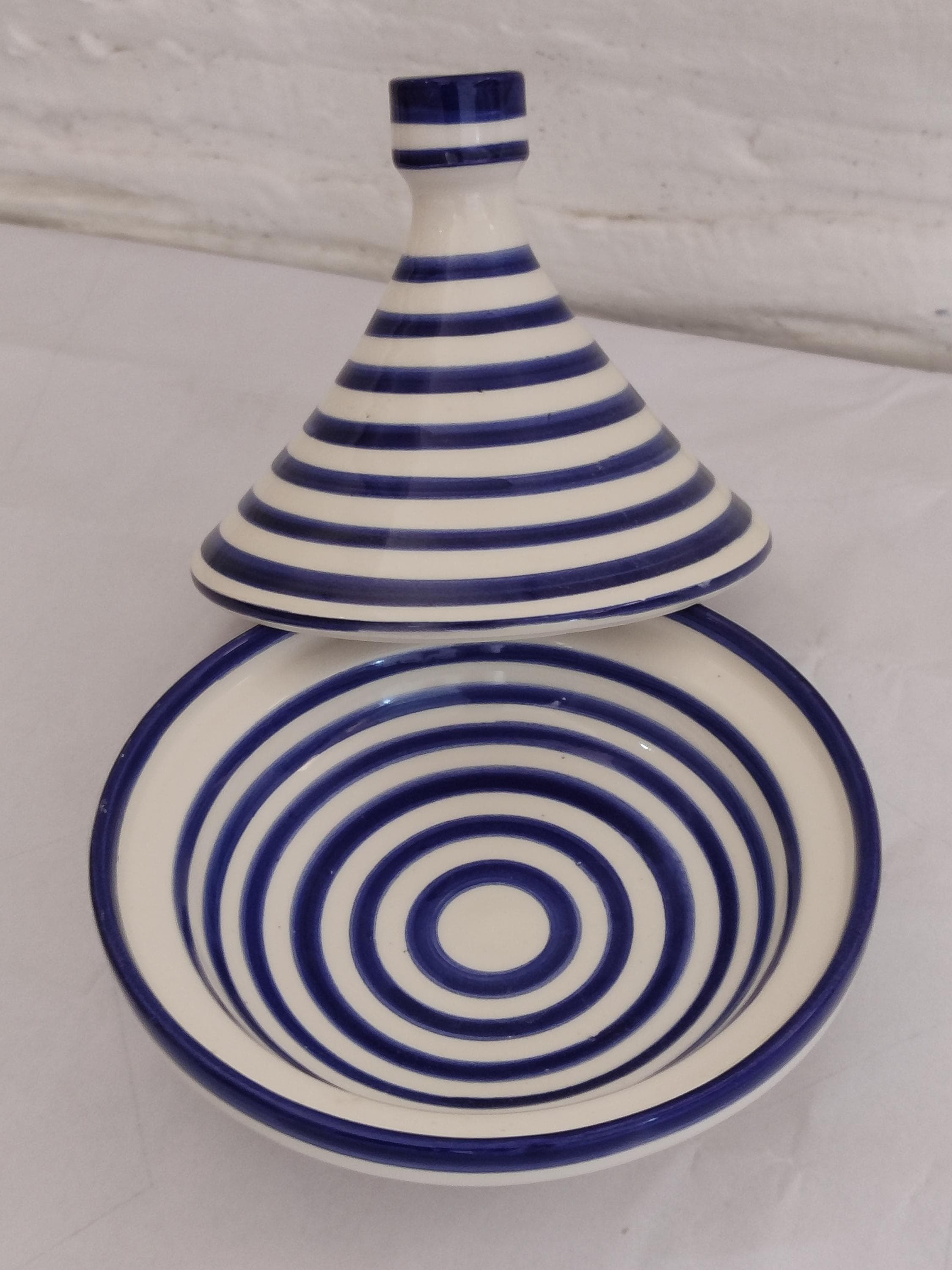 Our antique tagine recreates vintage Moroccan clay designs with authentic craftsmanship. This handmade clay tagine features distressed blue and white glazing that gives it a beautifully aged appearance while maintaining full functionality as cooking tagine. The thick ceramic walls provide excellent heat retention for slow-cooked Moroccan tagines. Measuring 13" across, it's perfect for family-sized portions. Each piece shows slight variations, proof of its handcrafted nature ceramics heritage.