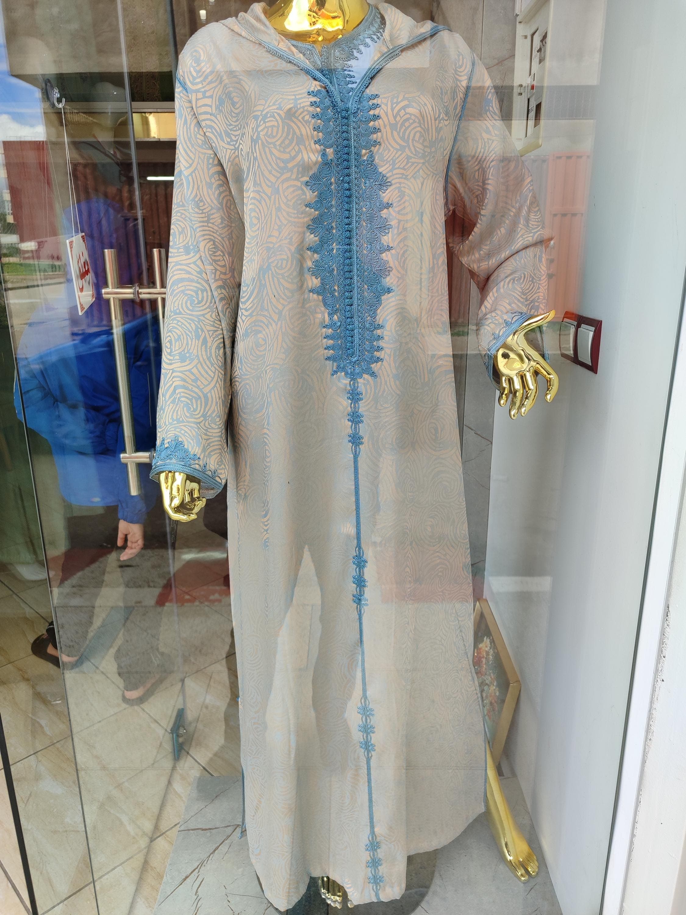 This handcrafted Moroccan jellaba features a smooth, lightweight fabric that feels cool and gentle against the skin. The sky blue material of this traditional Moroccan dress flows gracefully, with a silky texture that's both comfortable and luxurious. The jellaba marocaine offers a modest fashion option that doesn't compromise on comfort, making it perfect as an Islamic dress for daily wear or as a special Ramadan dress.