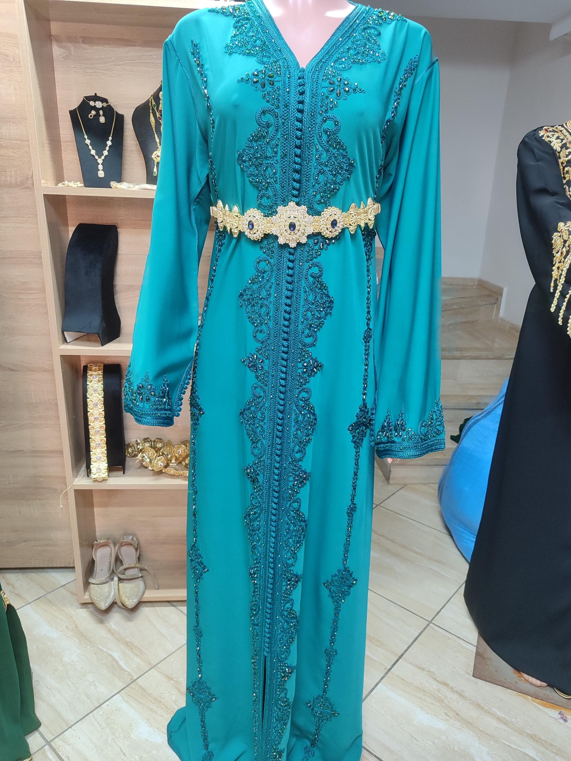 This exquisite Royal Wedding Dress combines traditional Moroccan takchita elegance with modern bridal sophistication. Handcrafted as a women's caftan marocain, it features intricate embroidery on premium fabrics with delicate beadwork. The two-piece Moroccan dress design includes a flowing overskirt and fitted underdress, perfect for nikah ceremonies or formal weddings.