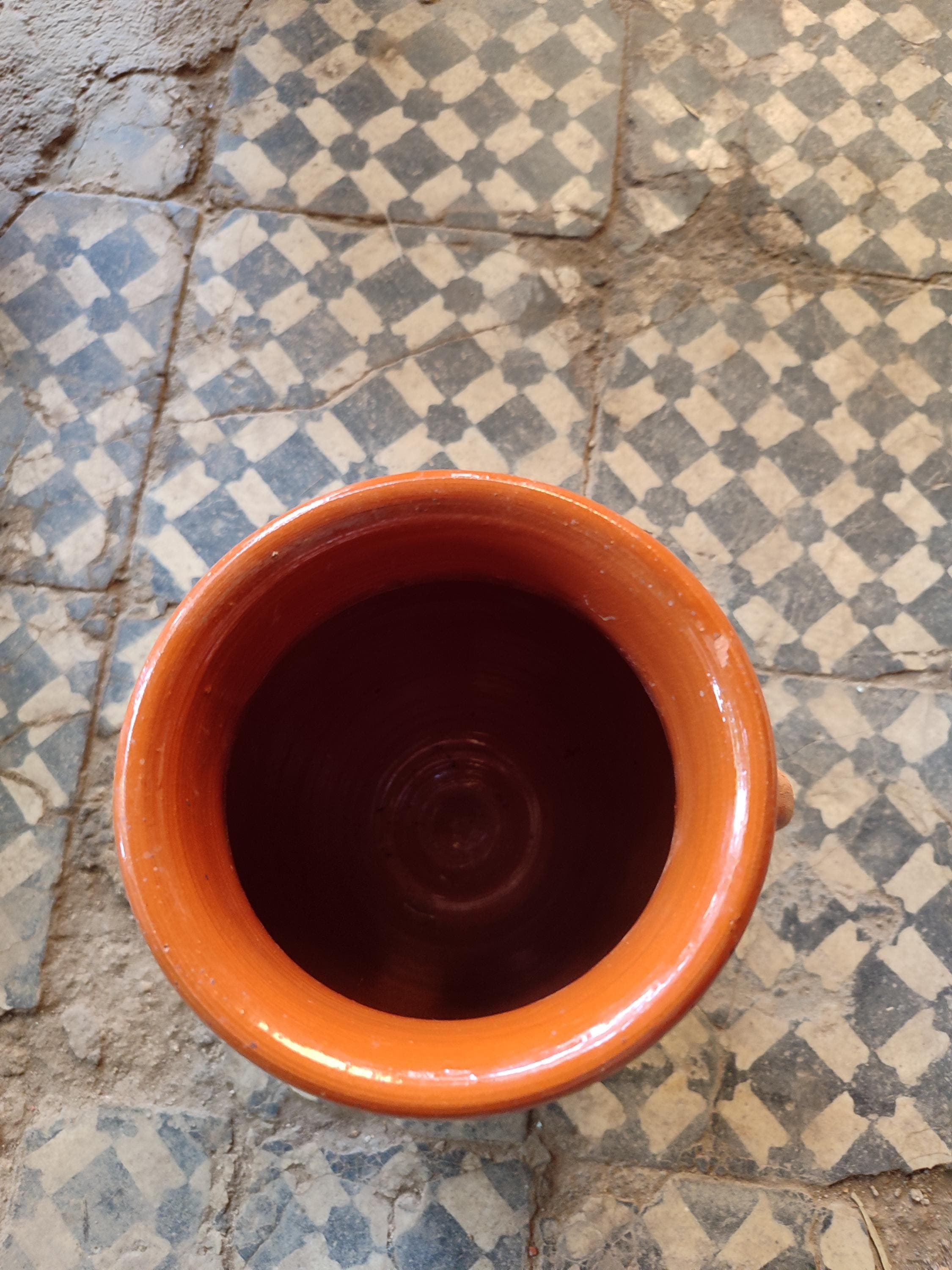 Our ceramic tanjia is handcrafted by skilled Moroccan artisans using time honored techniques. This terracotta dish features the distinctive urn shape essential for proper tanjia preparation, with a narrow neck that locks in moisture and flavor. The natural ceramic construction ensures even heat distribution for perfect slow cooked results every time. Excellent for preparing authentic Moroccan dishes or as a unique serving vessel.