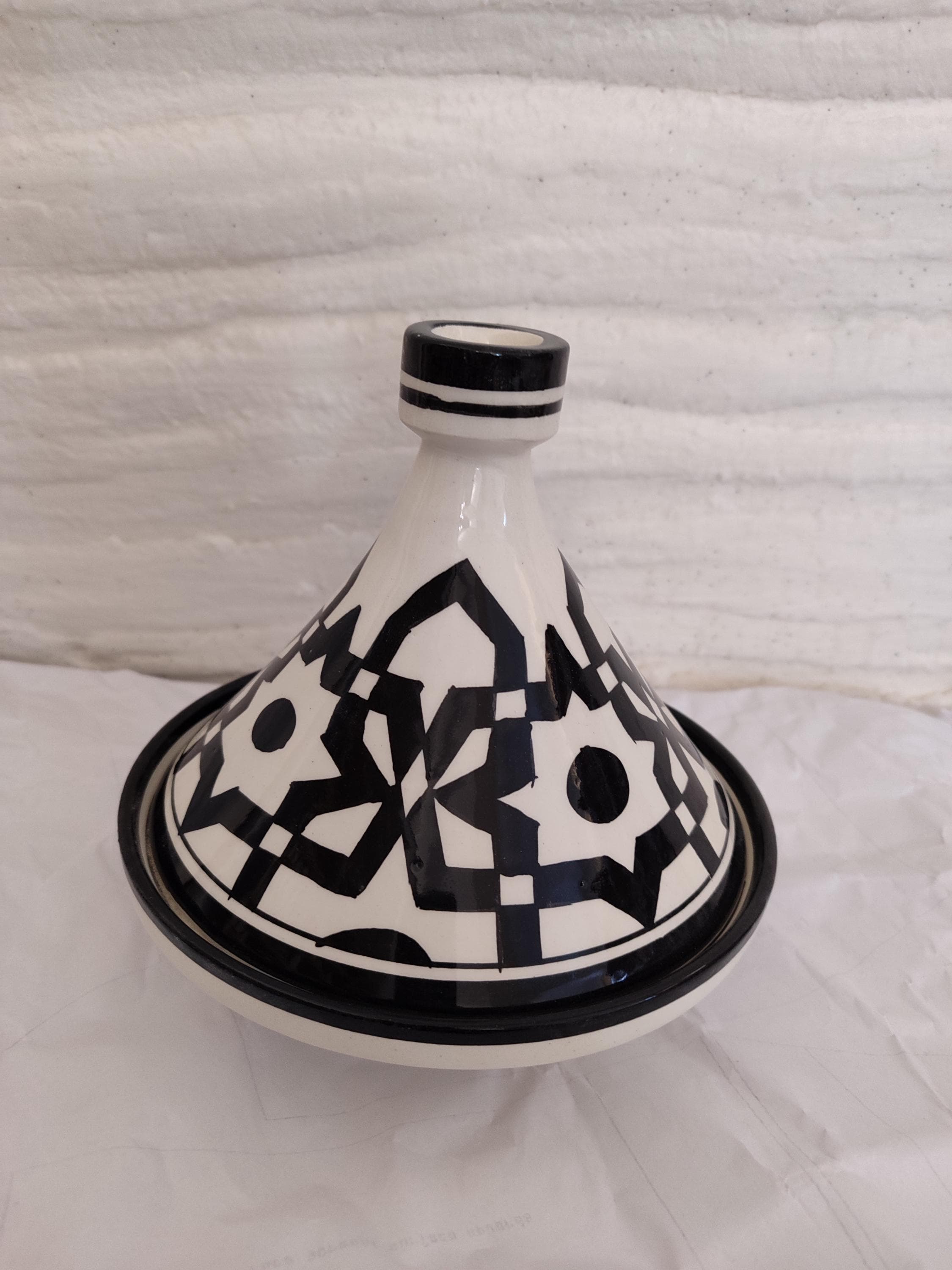 This Moroccan tagine / marokkanische Tajine is more than just a cooking pot—it's an experience. Crafted by artisans in Fez, it blends clay tajine / Tontopf-Tajine durability with striking black-and-white Islamic art motifs / islamische Keramik. Whether you're preparing lamb, chicken, or vegetables, this tagine / Kochtopf distributes heat evenly, ideal for slow cooking / schmoren rich Moroccan meals. A centerpiece in any kitchen.