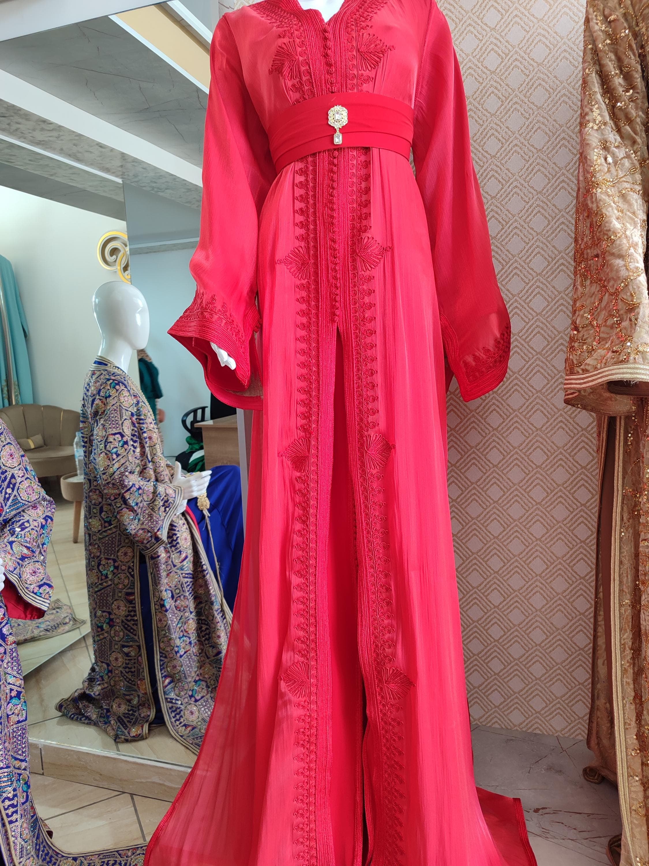Our Moroccan takchita represents the pinnacle of traditional Moroccan dress for special occasions. This two-piece koftan set features lavish embroidery on high-quality fabrics, creating a stunning luxury kaftan perfect for nikah dress ceremonies. The ornate detailing and flowing silhouette make this new caftan ideal for brides wanting cultural authenticity with contemporary style. The matching belt accentuates the waist beautifully, while the voluminous skirt creates graceful movement.