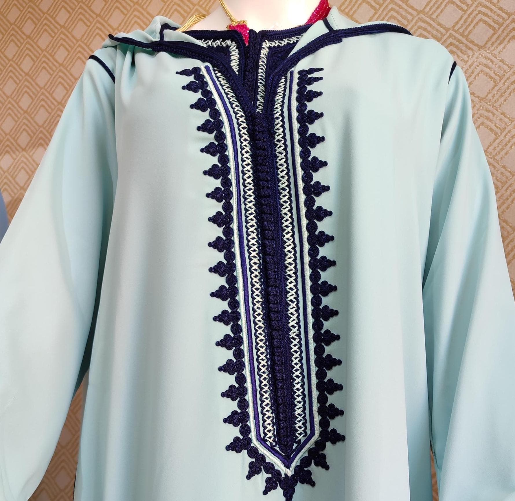 Our Traditional Jellaba is crafted from incredibly soft, lightweight fabric that feels gentle against your skin. This Moroccan jellaba has a smooth texture with slightly raised embroidery along the neckline and sleeves. When you run your fingers along the front of this Djellaba for Women, you'll feel the intricate handbeaded patterns that create a subtle texture contrast against the smooth background of this jellaba marocaine. The fabric drapes elegantly, neither too heavy nor too flimsy,