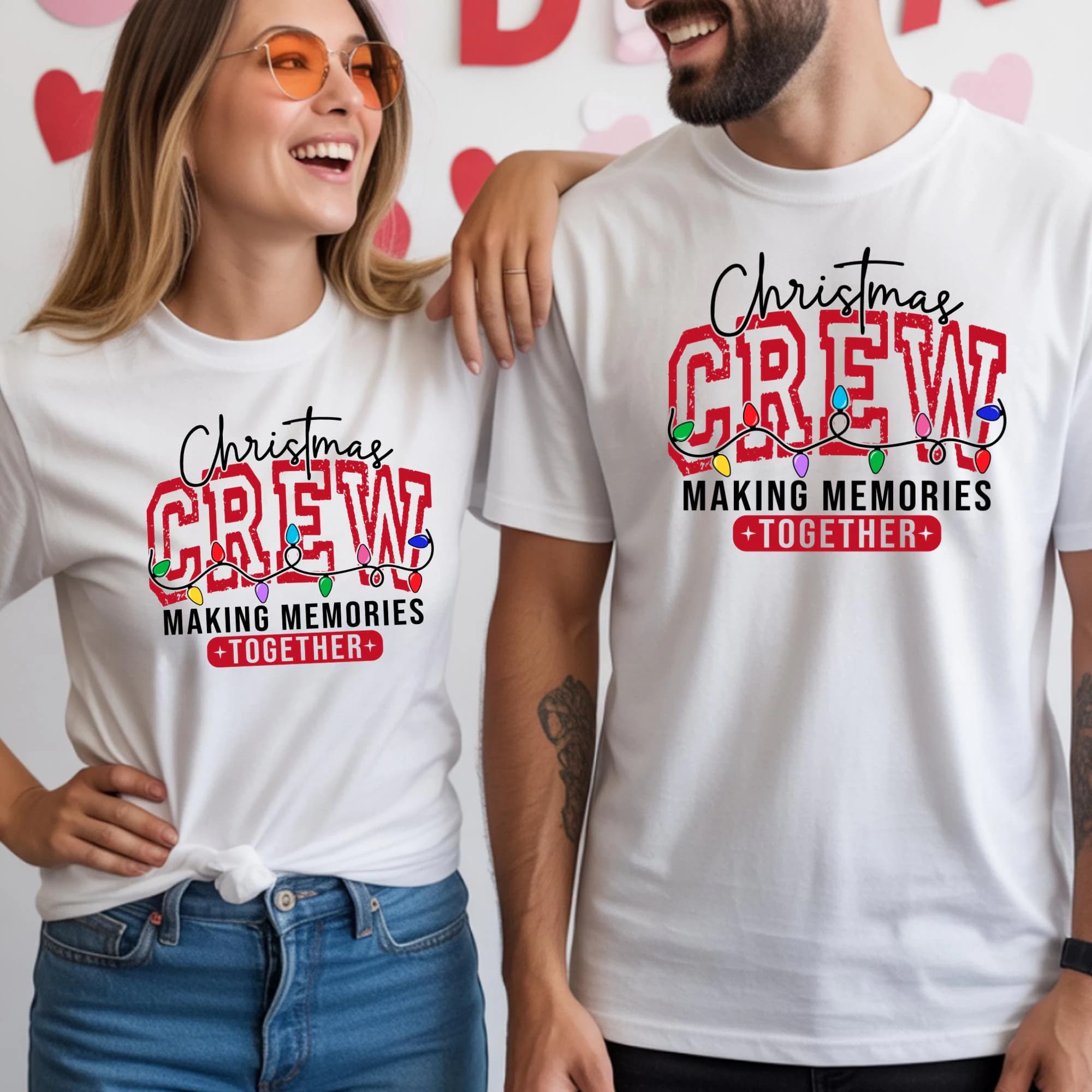 A smiling woman wearing a white t-shirt with a Christmas crew design and a man wearing a white t-shirt with a similar design.