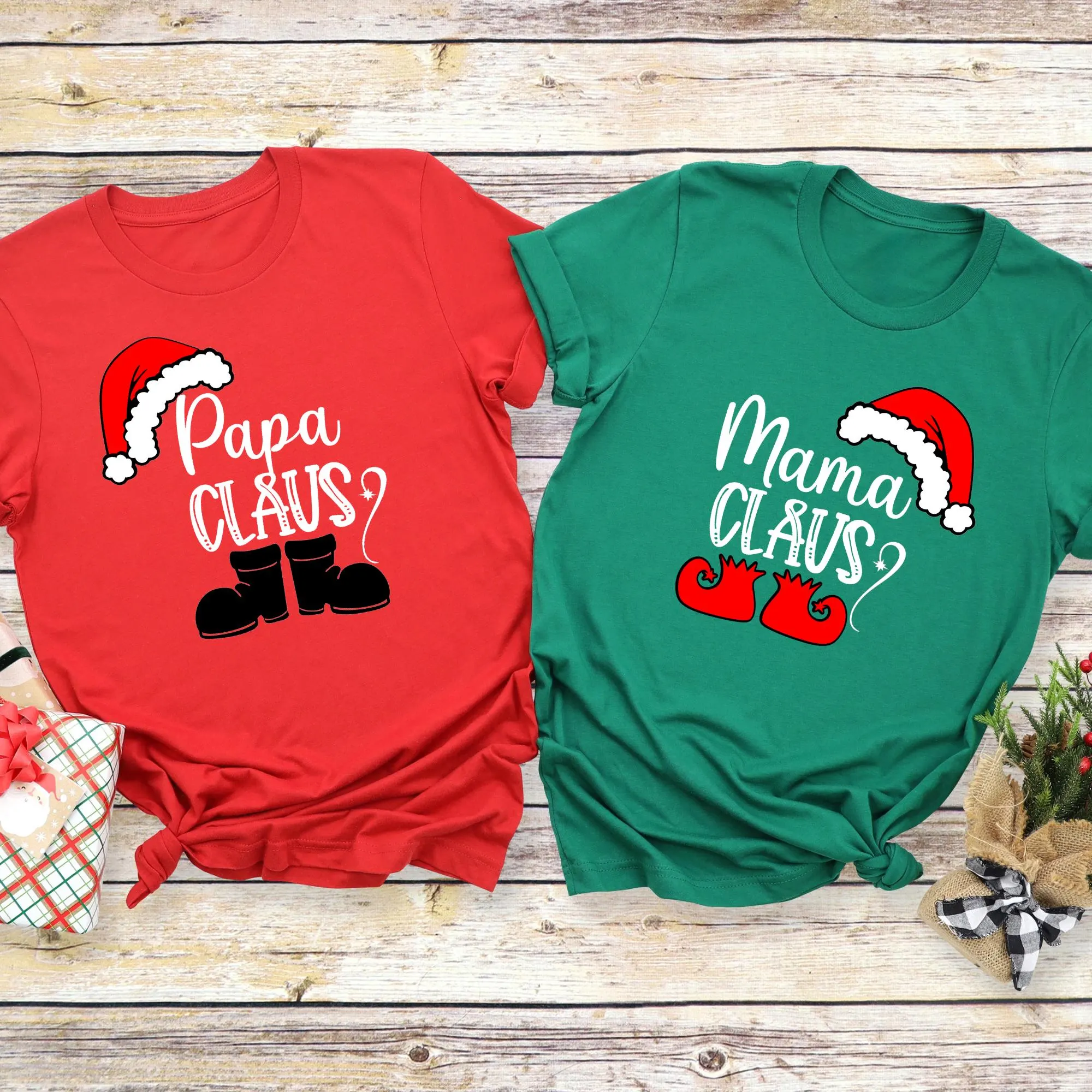 two t-shirts with Christmas-themed designs, one red and one green, placed on a wooden surface.