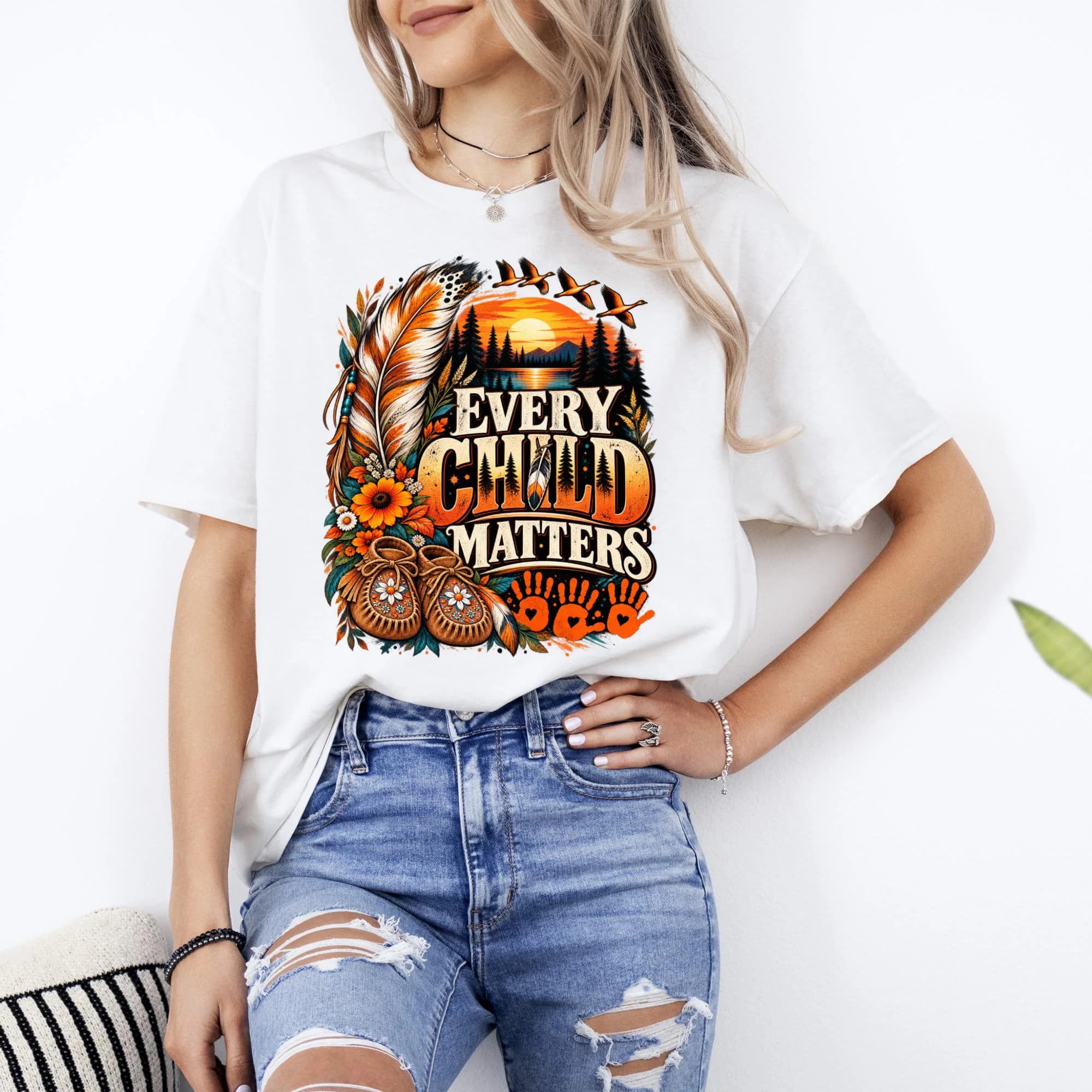 White t-shirt with "Every Child Matters" design featuring feathers, moccasins, and handprints.