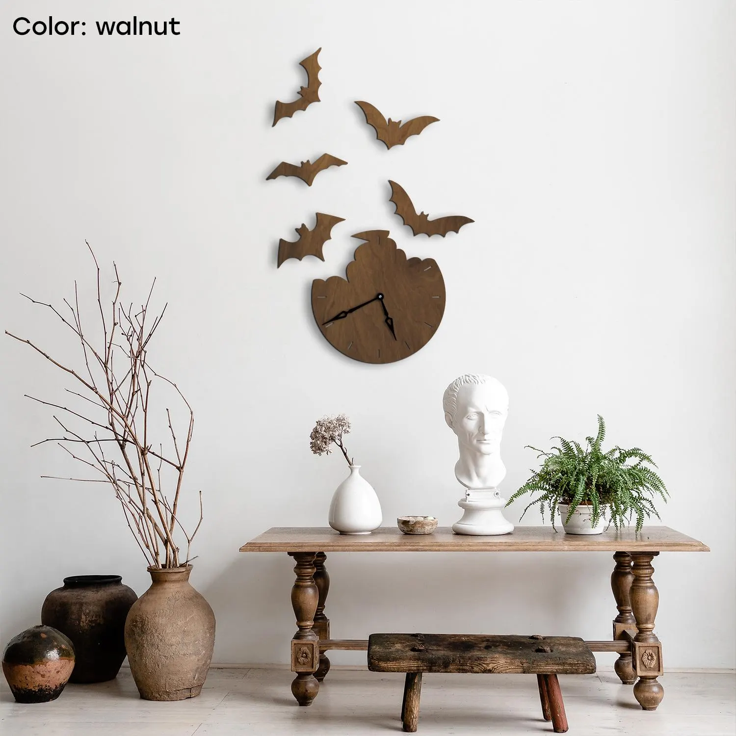 May include: A walnut-colored wooden wall clock with a bat design, featuring a broken circle shape and black clock hands. Five wooden bat silhouettes are arranged above the clock. The clock is mounted on a white wall.