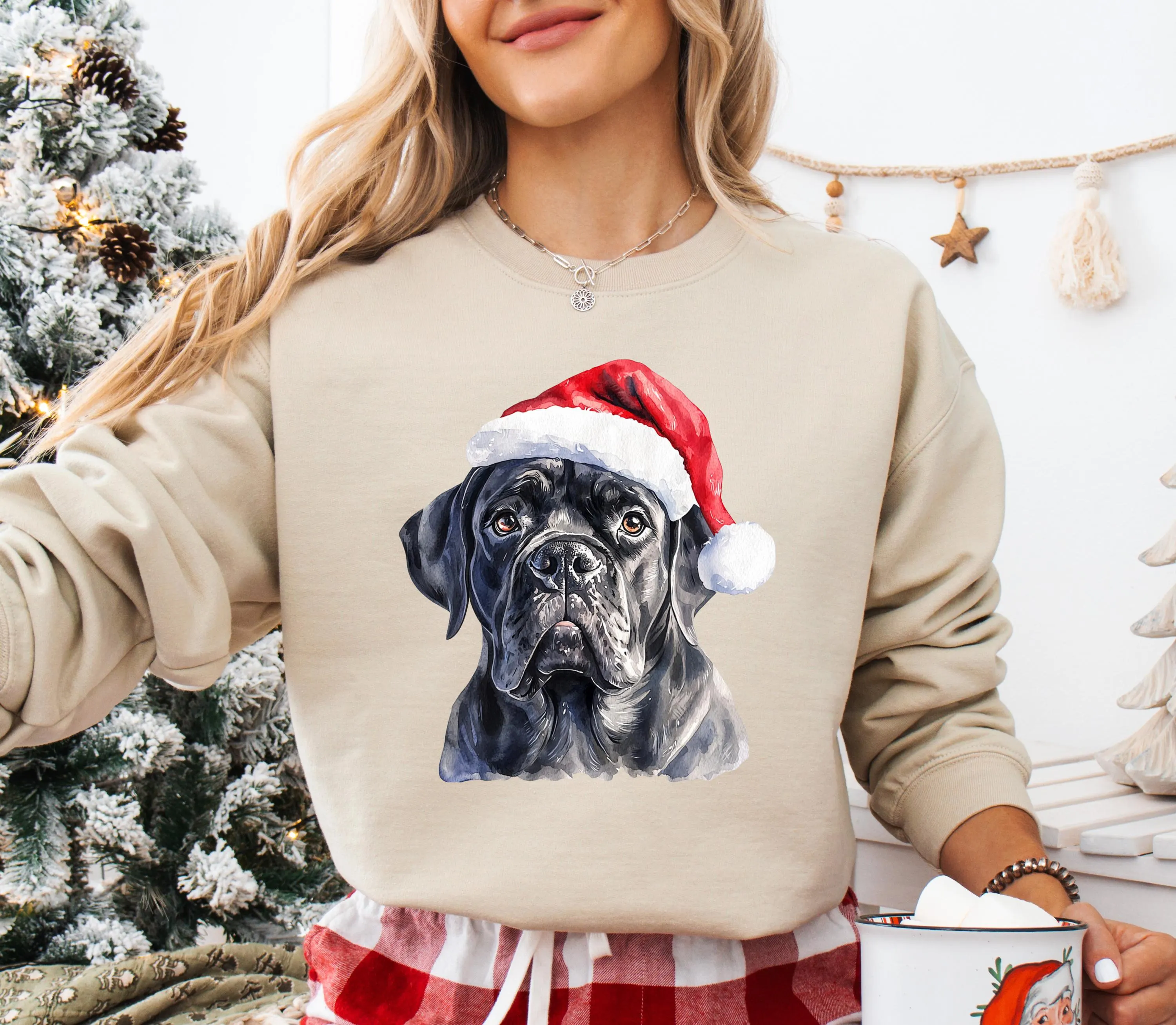 A woman wearing a beige sweater with a black dog wearing a Santa hat.