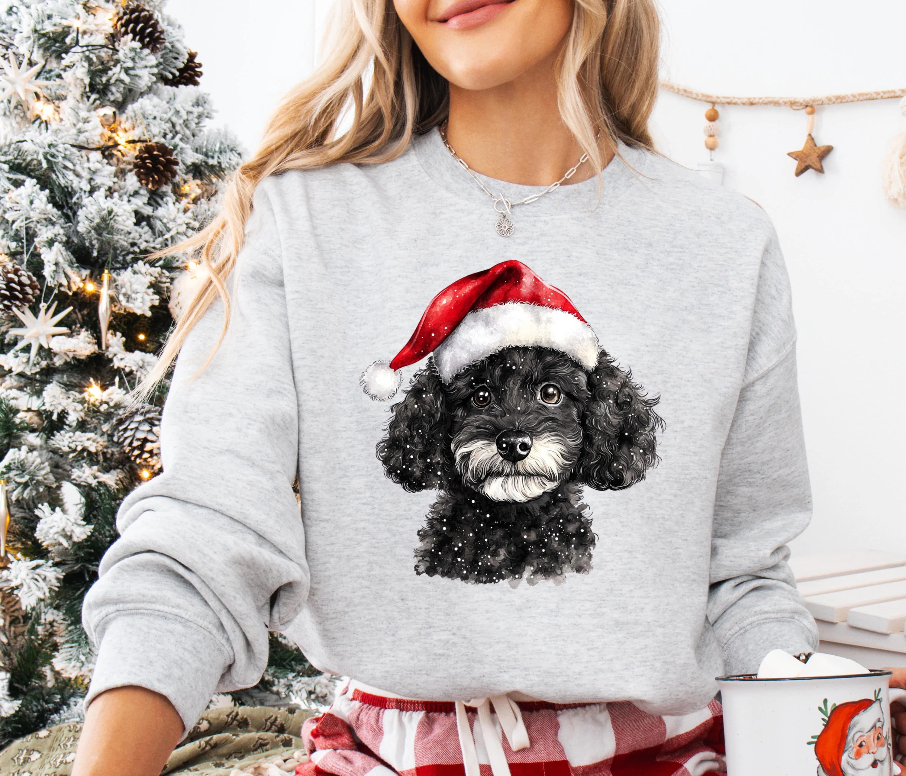 A woman wearing a gray sweatshirt with a black and white dog wearing a Santa hat.