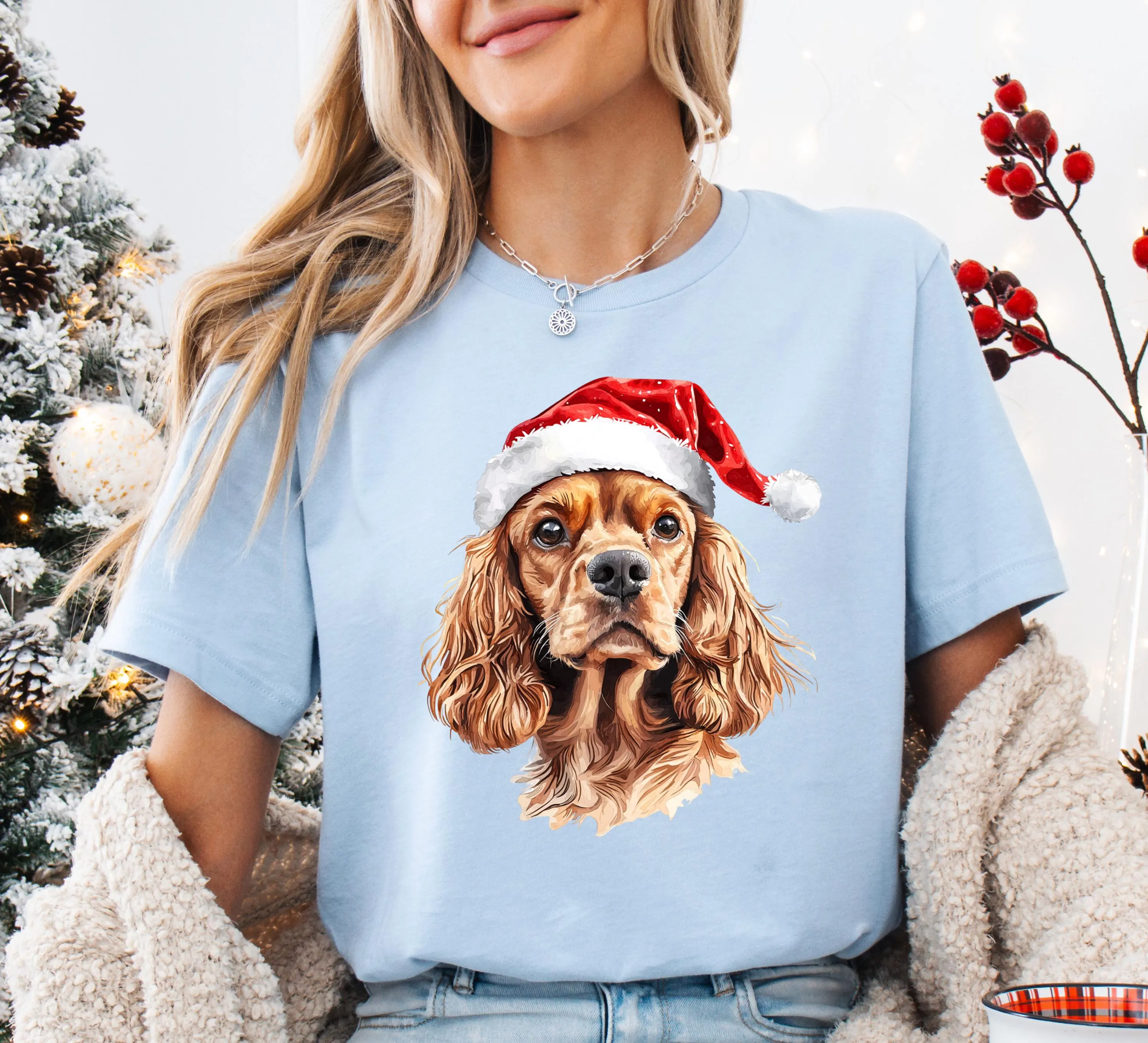 A woman wearing a light blue t-shirt with a picture of a dog wearing a Santa hat.