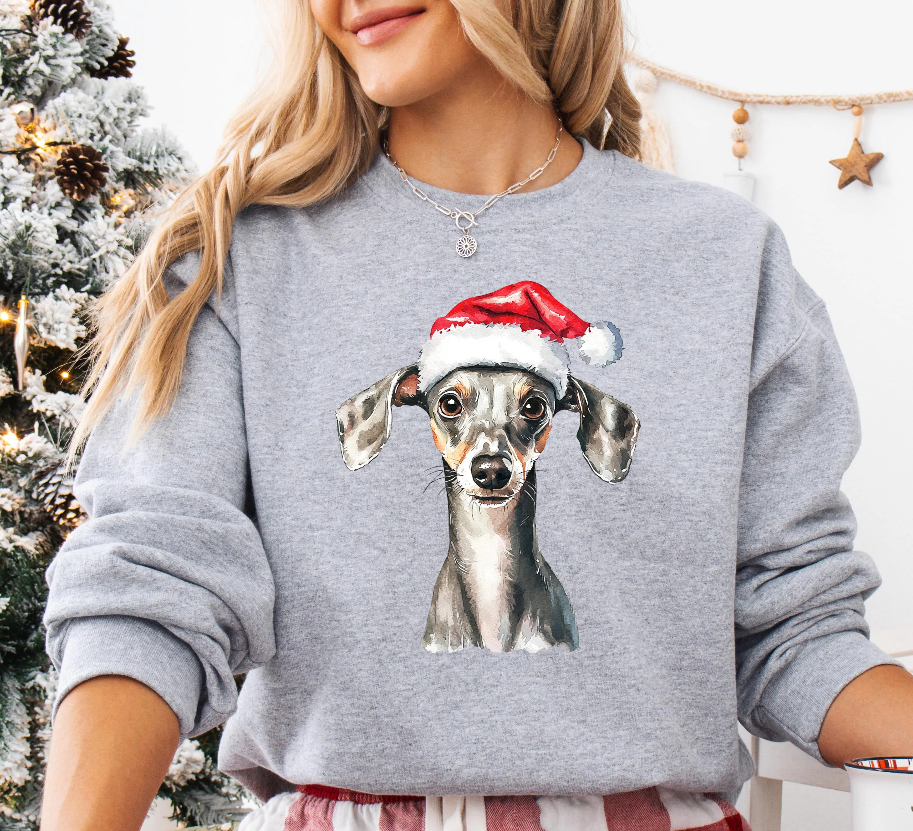 A woman wearing a gray sweatshirt with a printed image of a dog wearing a Santa hat.