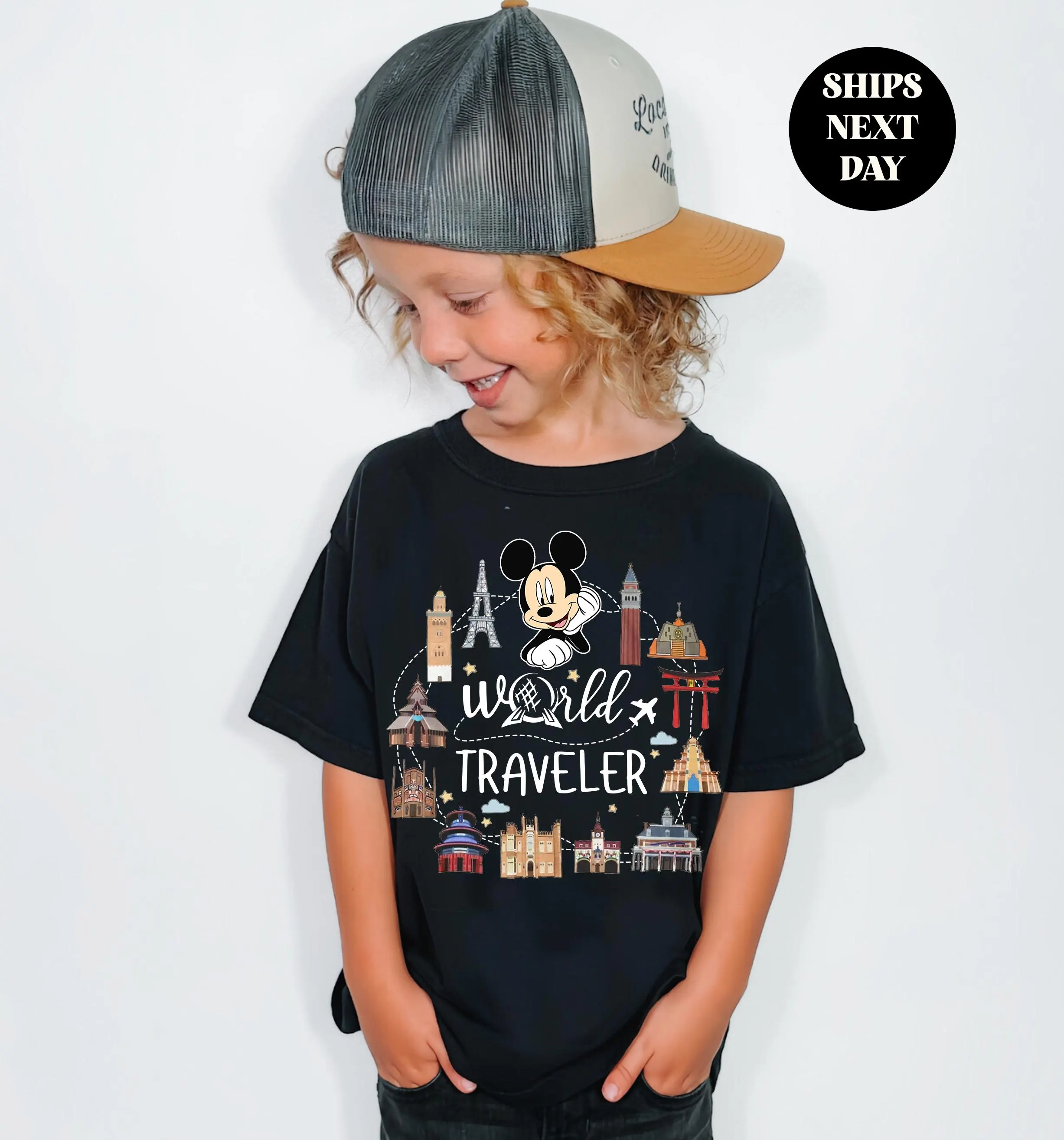 A young child wearing a black t-shirt with a cartoon character and text, smiling and looking down.