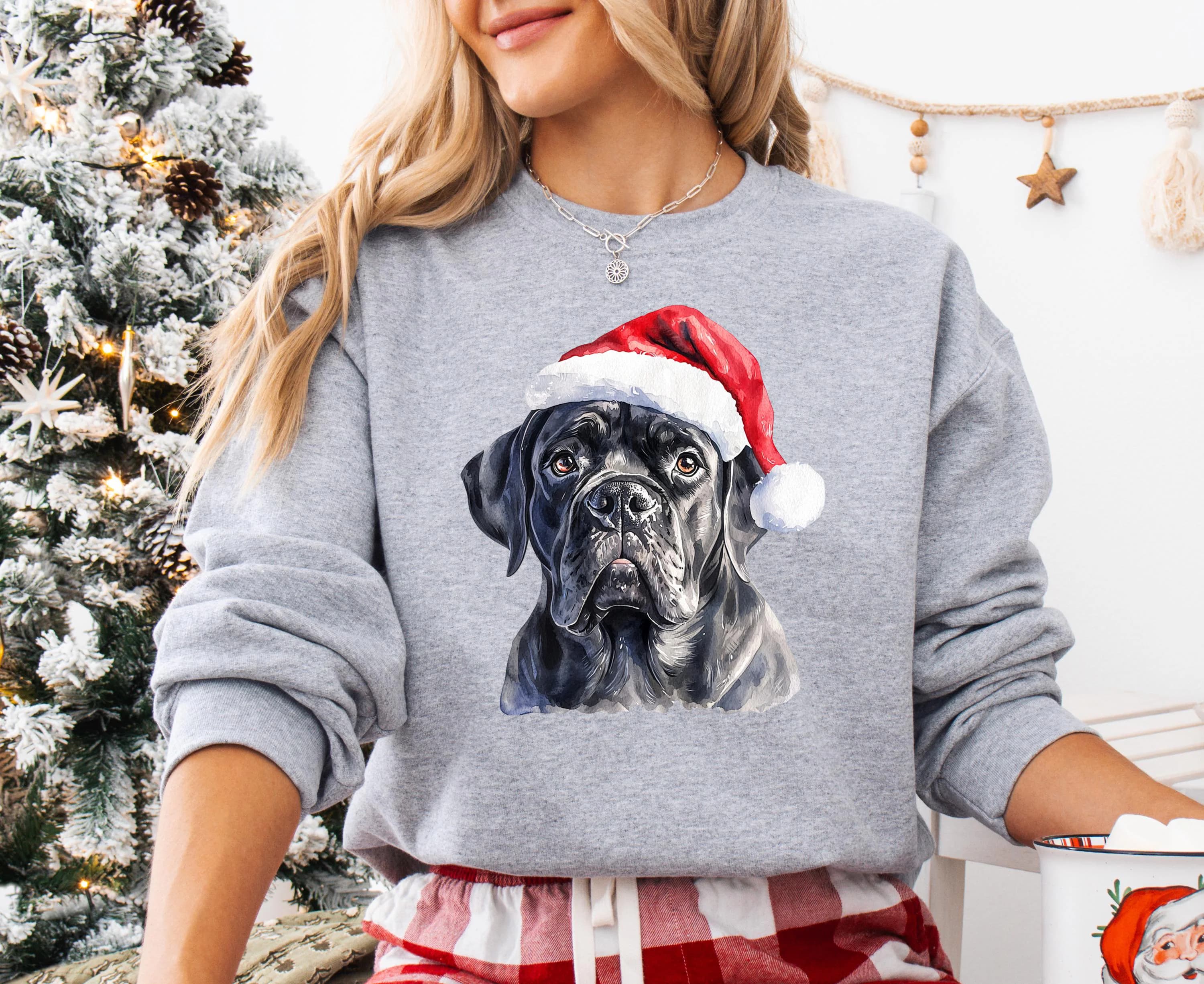 A woman wearing a gray sweatshirt with a black dog wearing a Santa hat.
