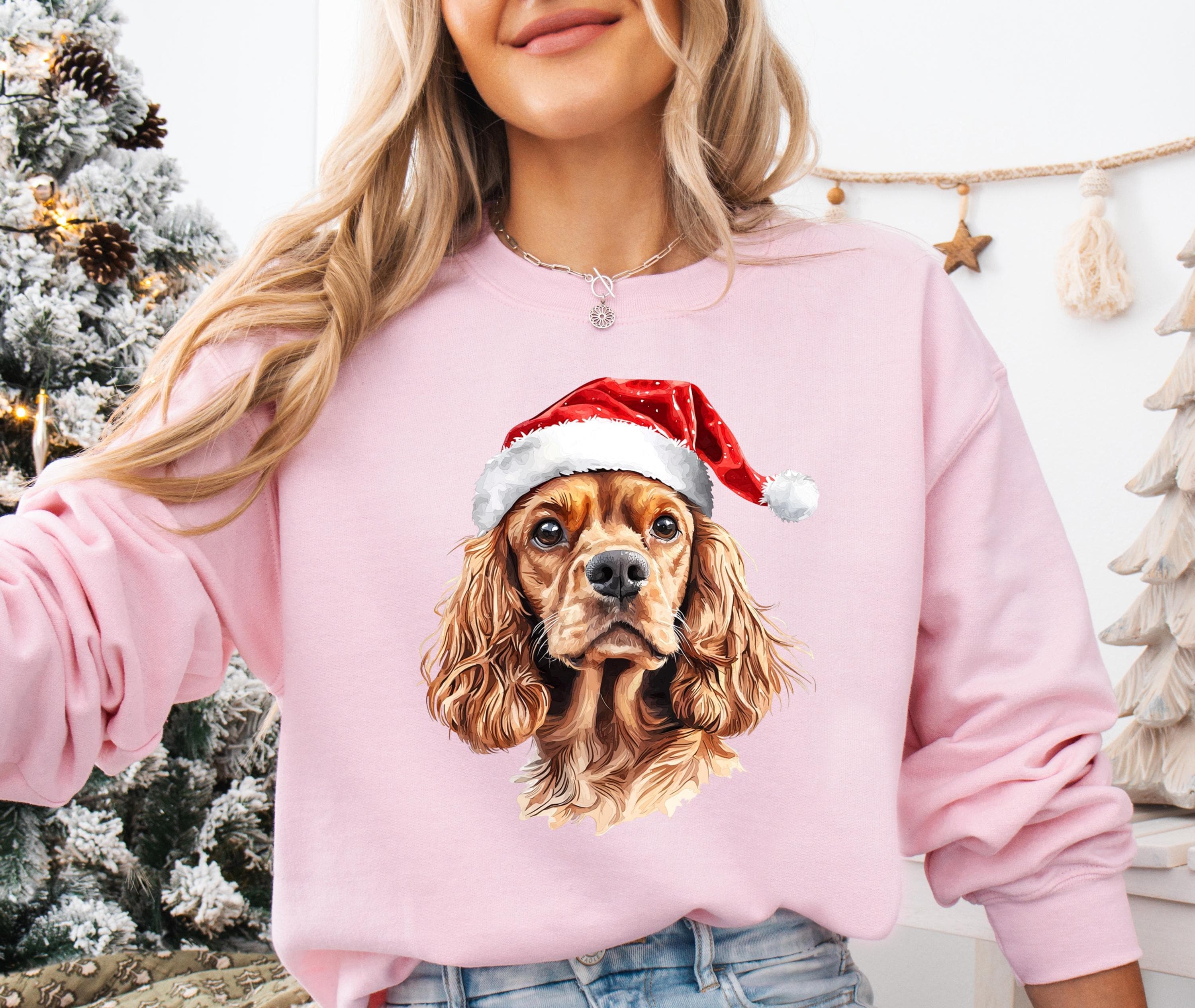 A woman wearing a pink sweatshirt with a picture of a dog wearing a Santa hat.