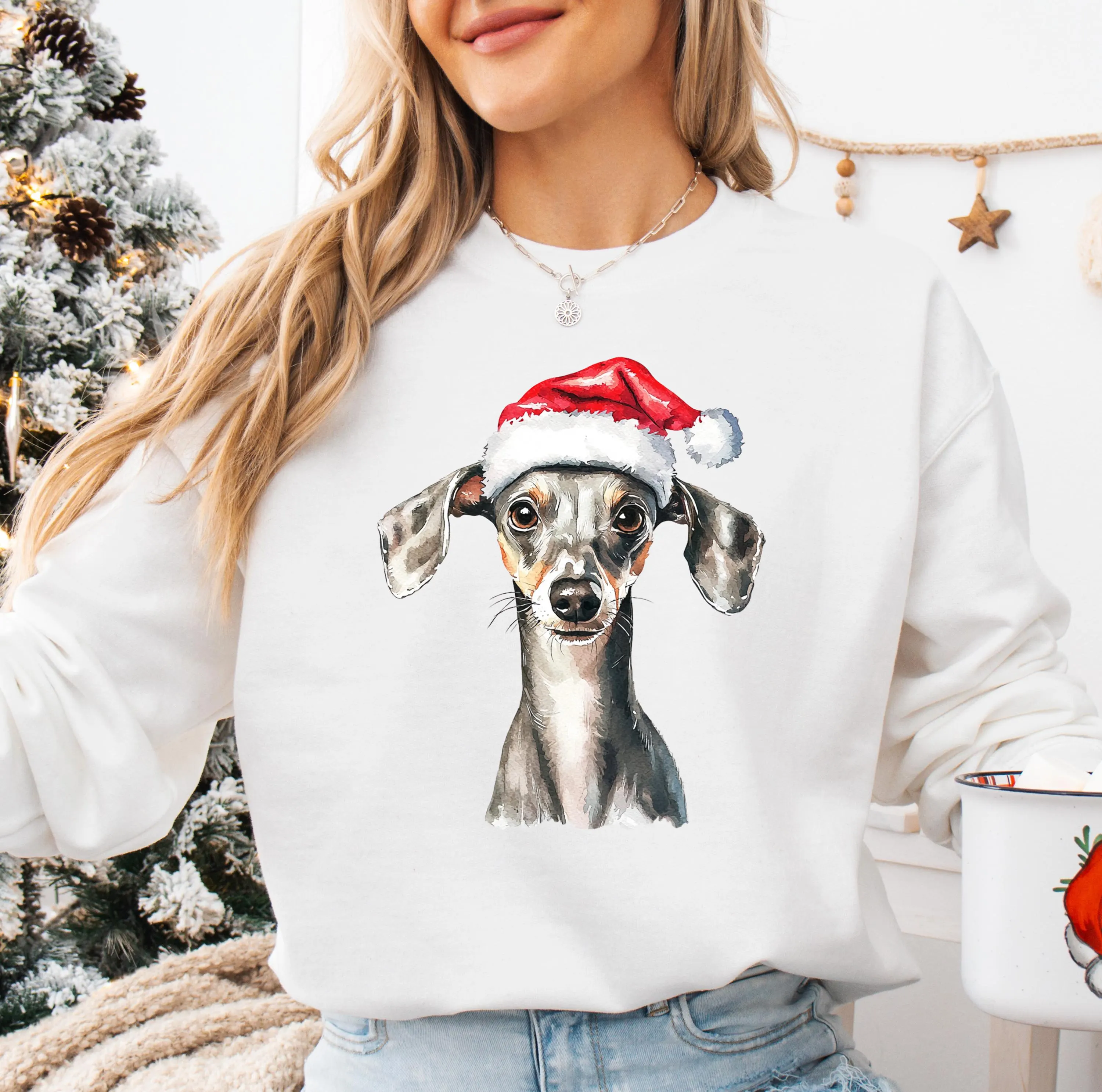 A woman wearing a white sweatshirt with a picture of a dog wearing a Santa hat.